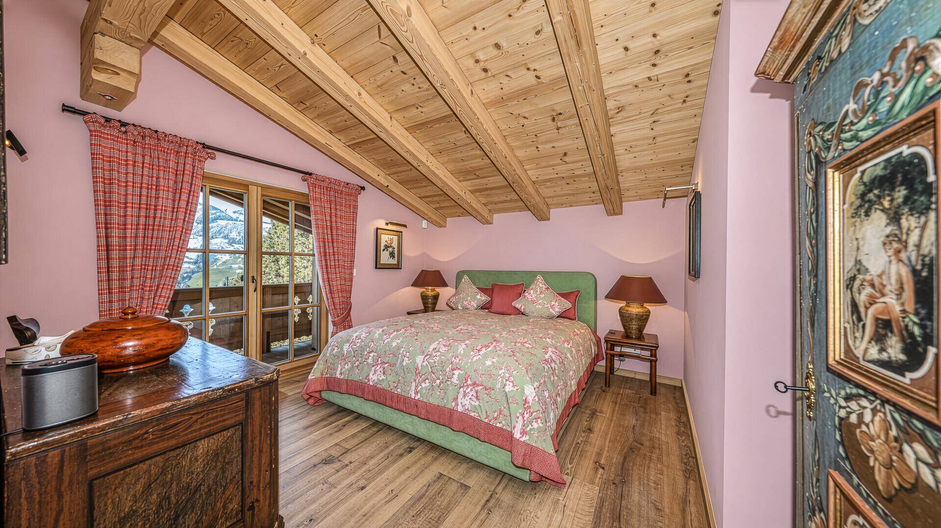 Romantisches Schlafzimmer mit Holzbalkendecke, Balkonzugang und Bergblick.