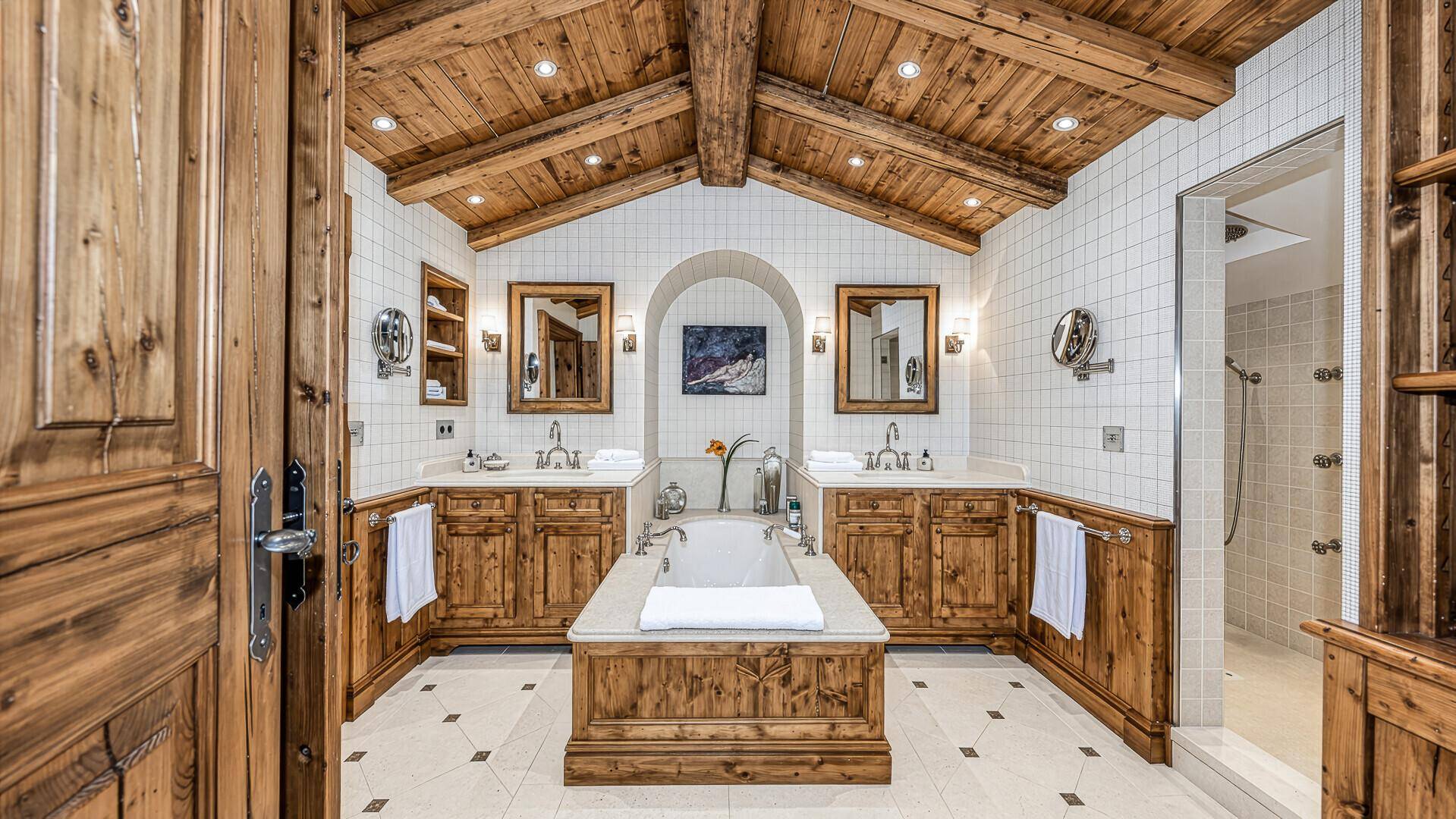 Luxuriöses Badezimmer mit Holzbalkendecke, Doppelwaschbecken und integrierter Badewanne.