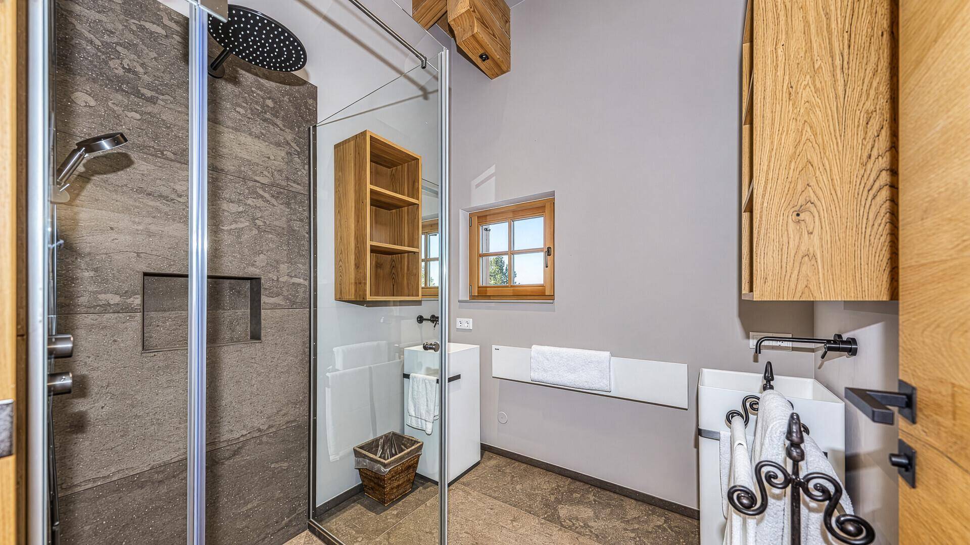 Modernes Badezimmer mit Dusche, Fenster und Holzschränken.