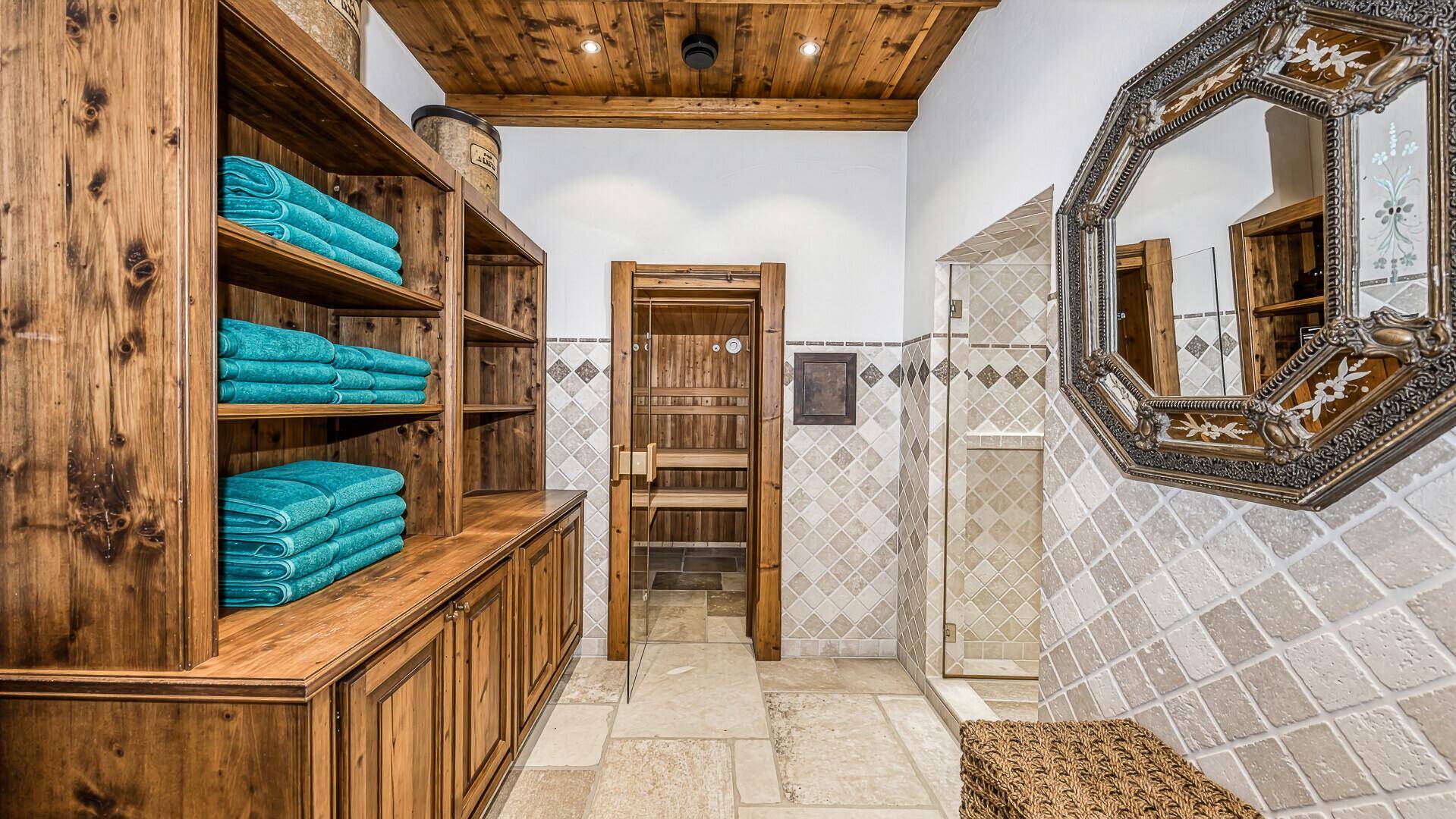 Wellnessbereich mit Sauna, Dusche und rustikalen Holzregalen für Handtücher.