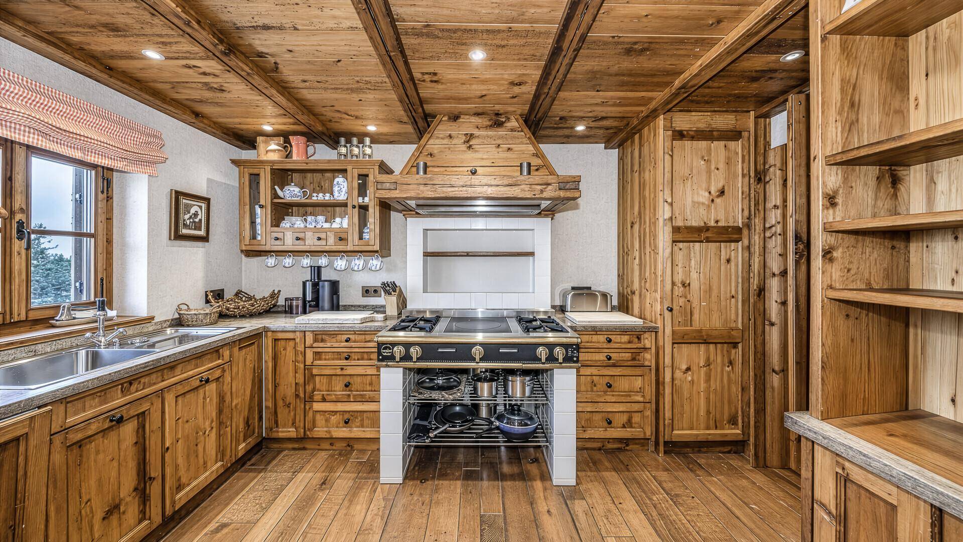 Traditionelle Holzküche mit rustikalen Schränken, großem Herd und Holzbalkendecke.