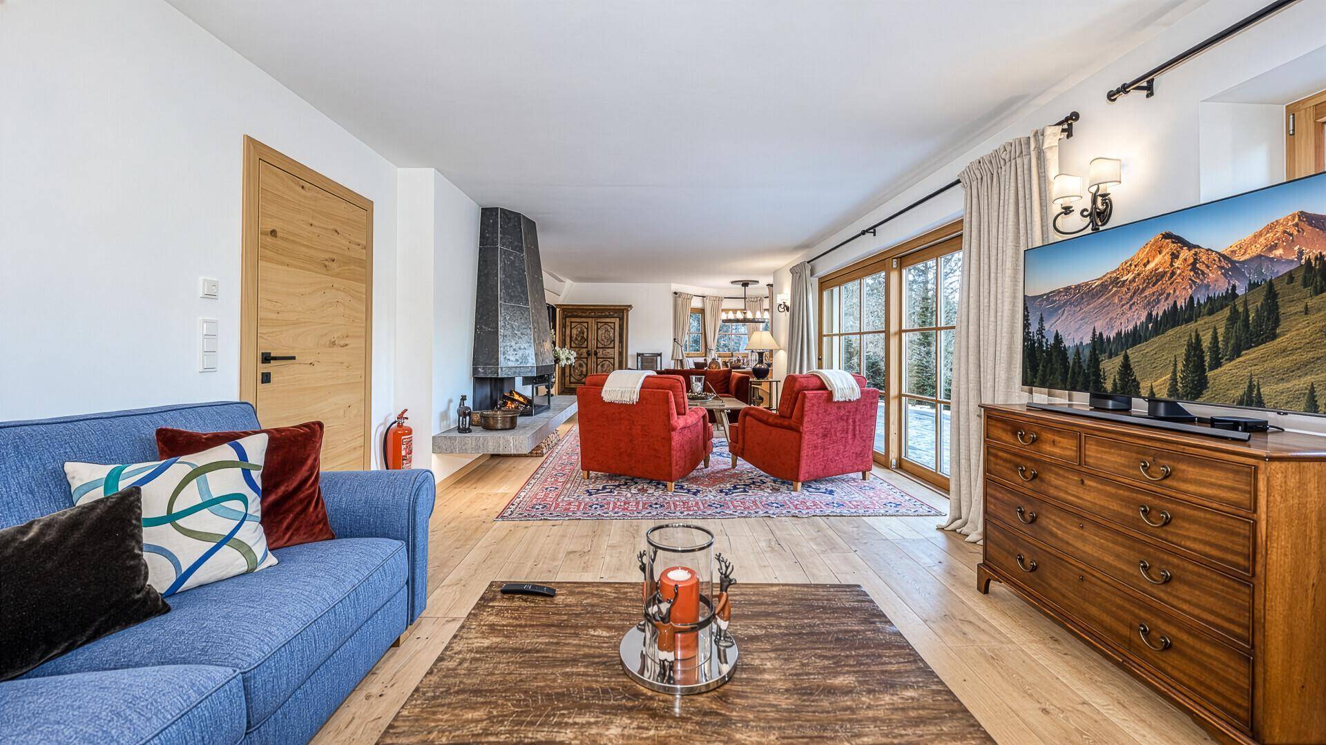 Geräumiges Wohnzimmer mit modernem Kamin, Holzboden und großen Fenstern mit Bergblick.