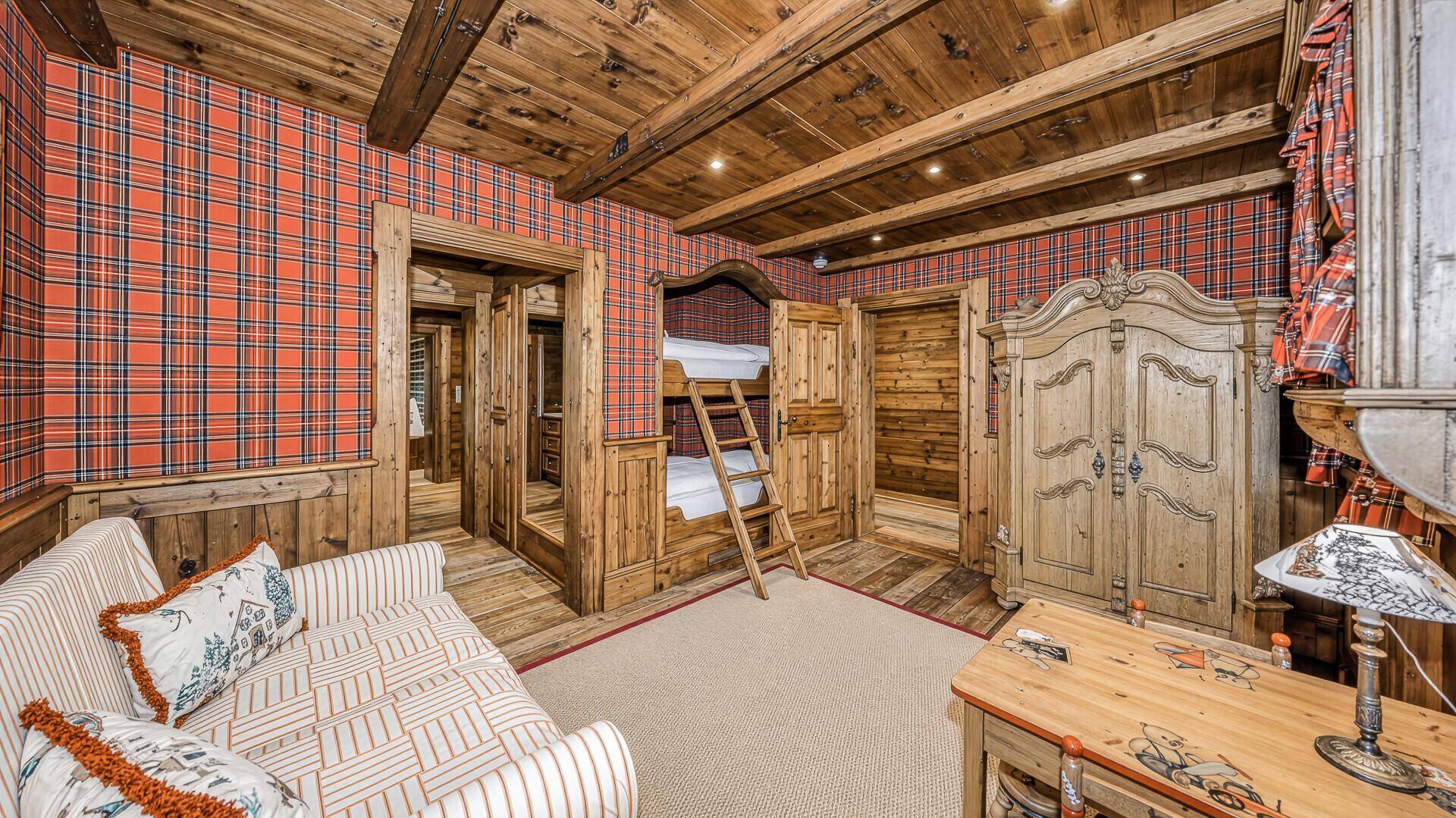 Kinderzimmer im alpinen Stil mit Etagenbett, karierter Tapete und traditionellem Holzschrank.