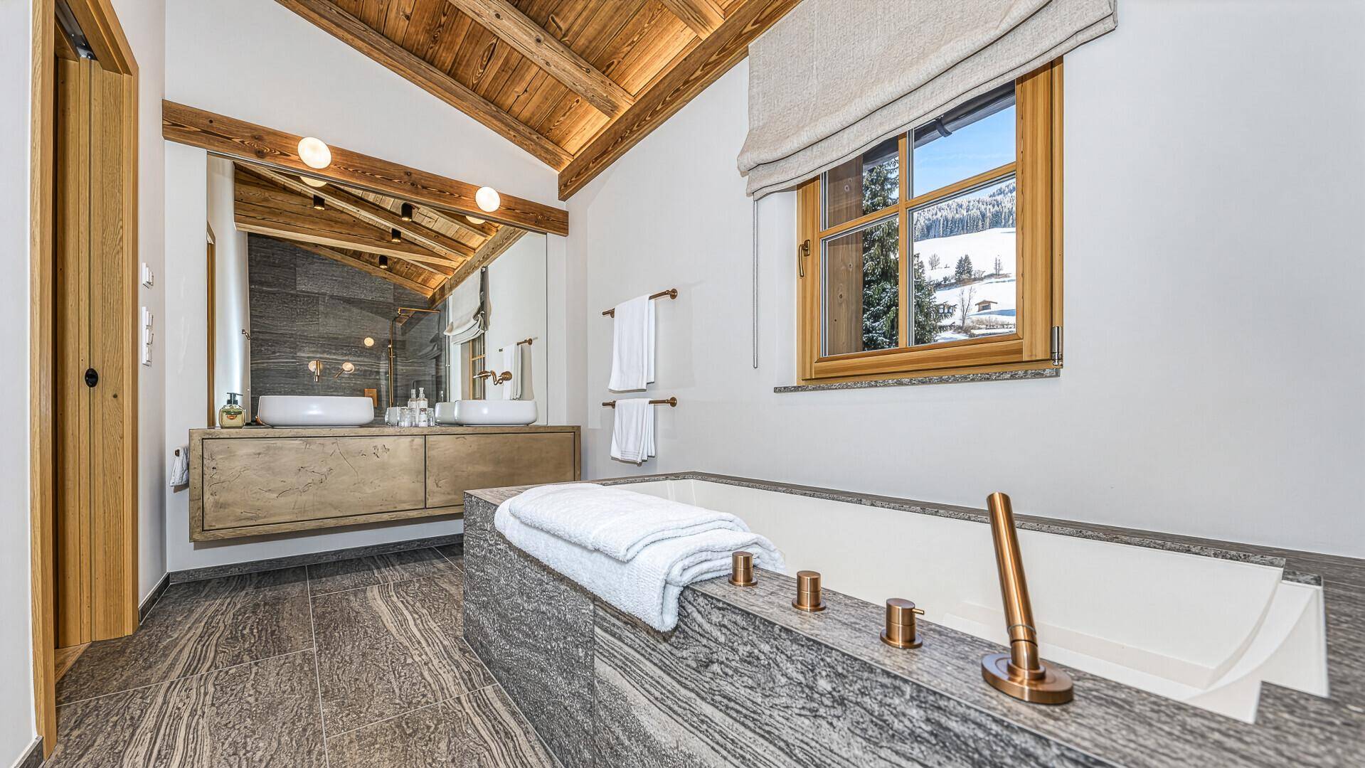 Modernes Badezimmer mit freistehender Badewanne, Doppelwaschbecken und Bergblick.