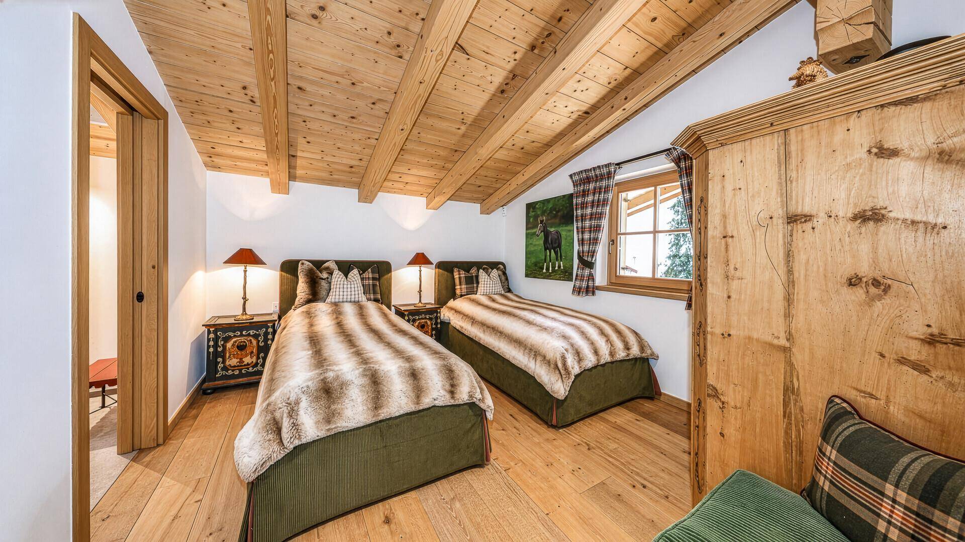 Schlafzimmer mit zwei Einzelbetten, Holzbalkendecke und traditionellem Kleiderschrank.