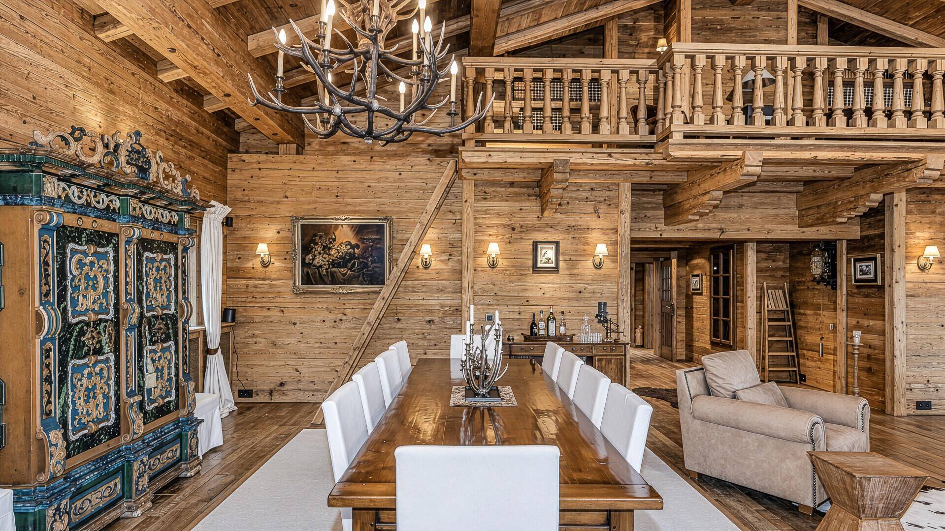Eleganter Essbereich mit langem Holztisch, weißen Stühlen und einem verzierten Schrank.