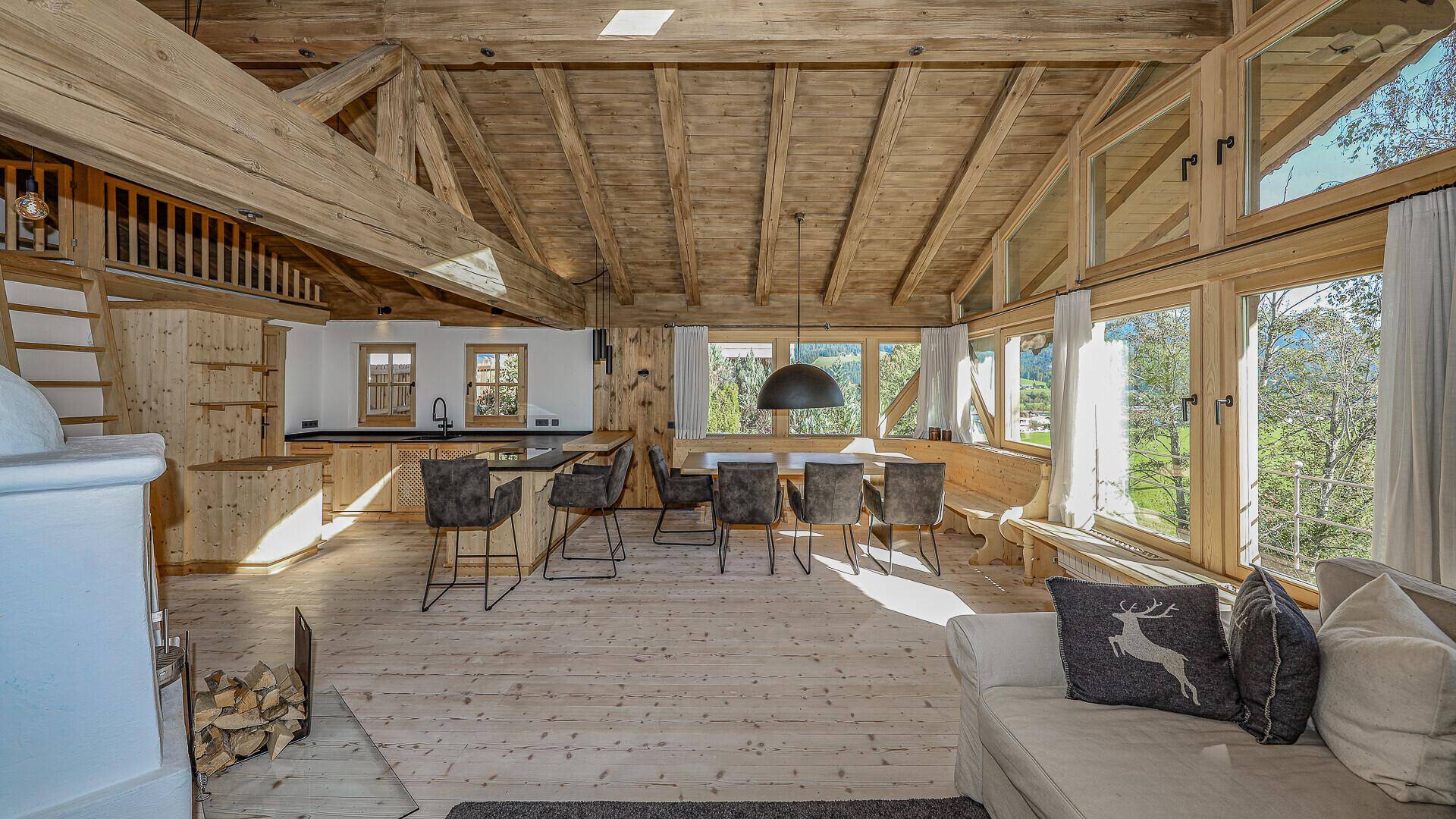 Weitläufiger Wohnbereich mit Holzbalkendecke, Essbereich und offener Küche.