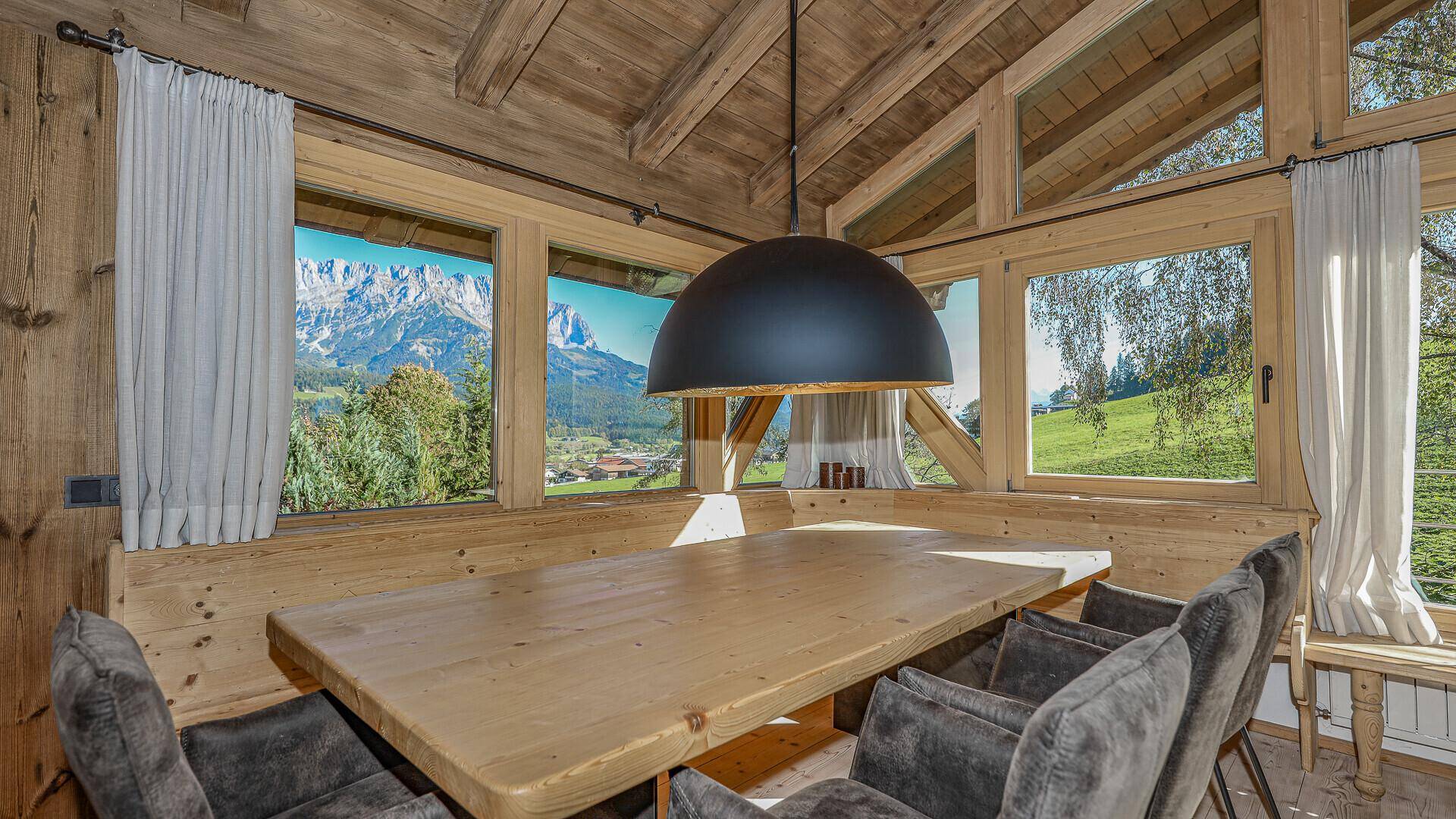 Essbereich mit Holztisch, bequemen Stühlen und Panoramablick auf die Berge.