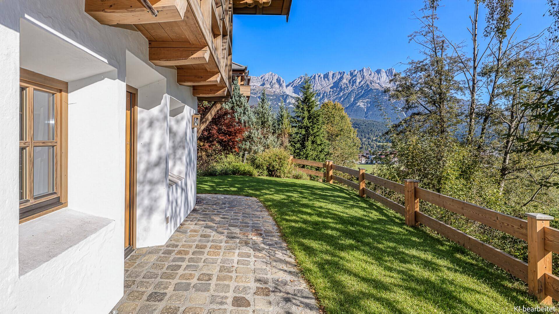 Gepflasterte Terrasse neben dem Haus mit Blick auf den Garten und die Berge.