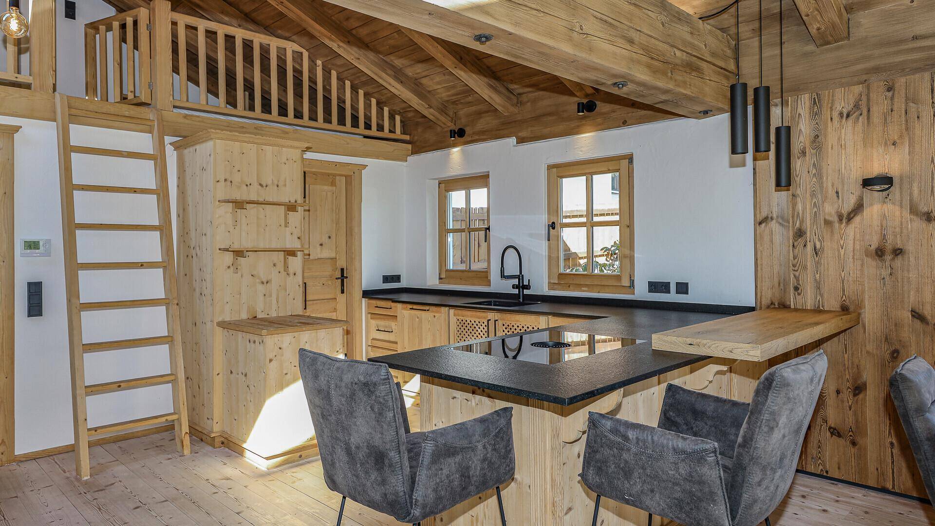 Moderne Holzküche mit Kochinsel, Barhockern und integrierten Geräten.
