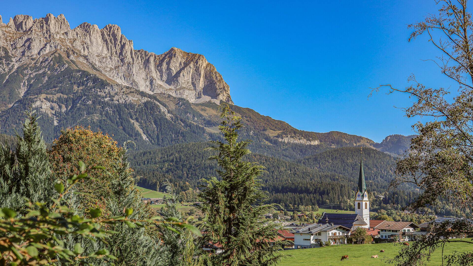 Malerischer Blick auf das Dorf mit Kirche und die umliegende Berglandschaft.