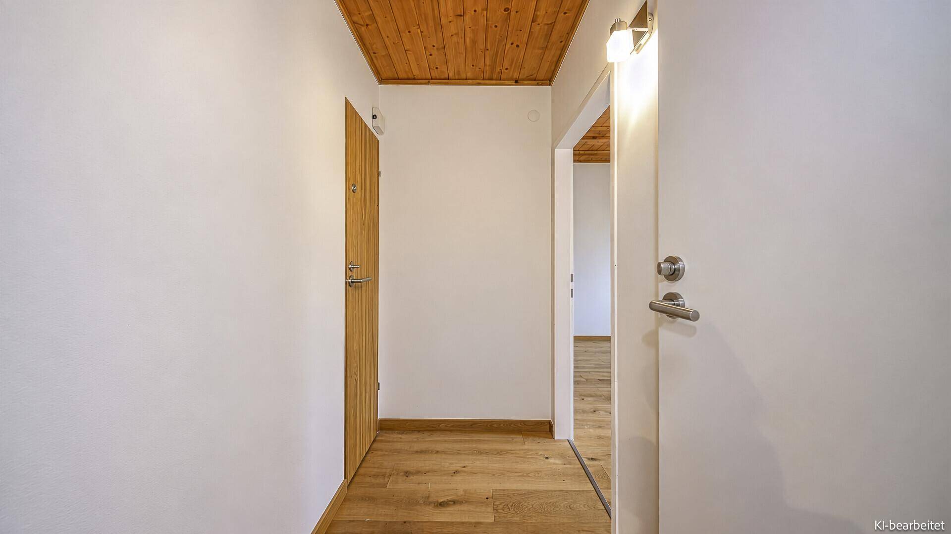 Heller Flur mit Holzboden und Holzdecke, der zu verschiedenen Räumen der Wohnung führt.