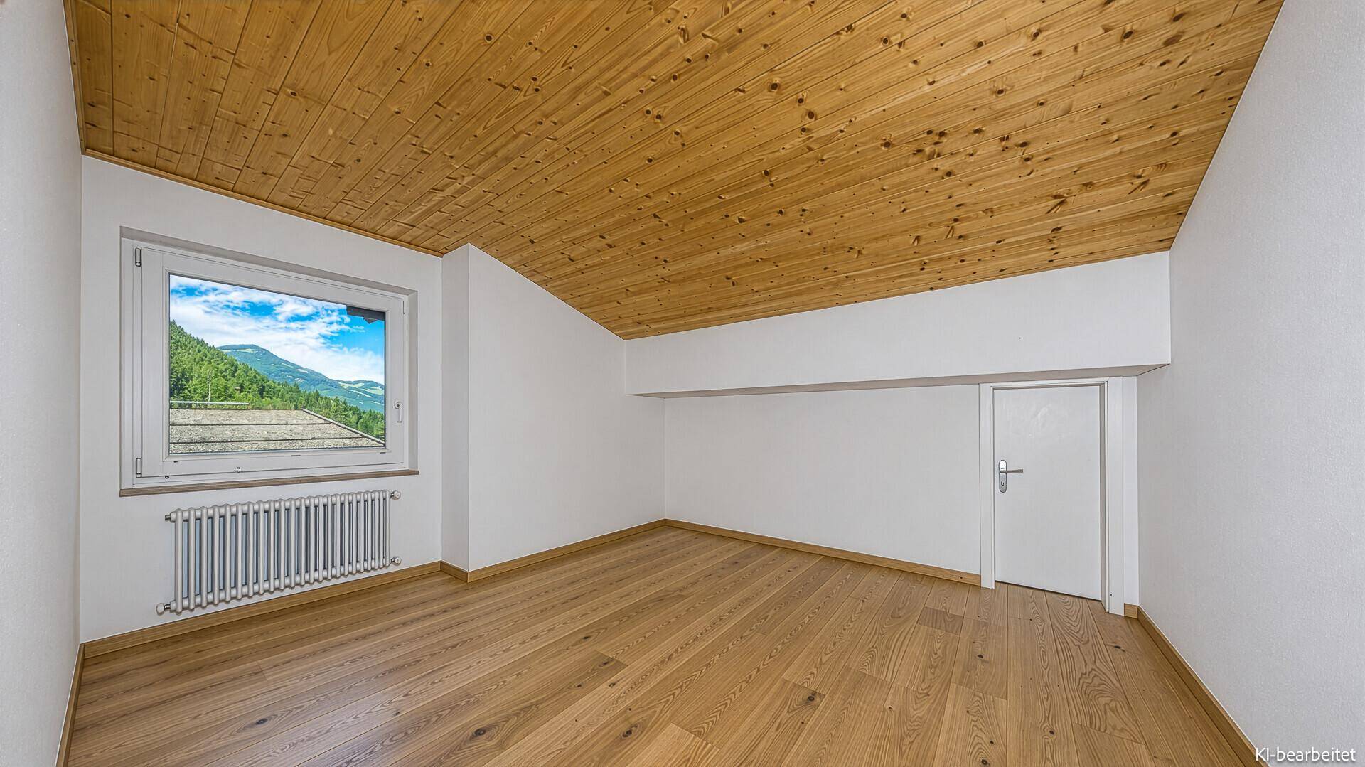 Helles Dachzimmer mit schräger Holzdecke, Parkettboden und Fenster mit Bergblick.