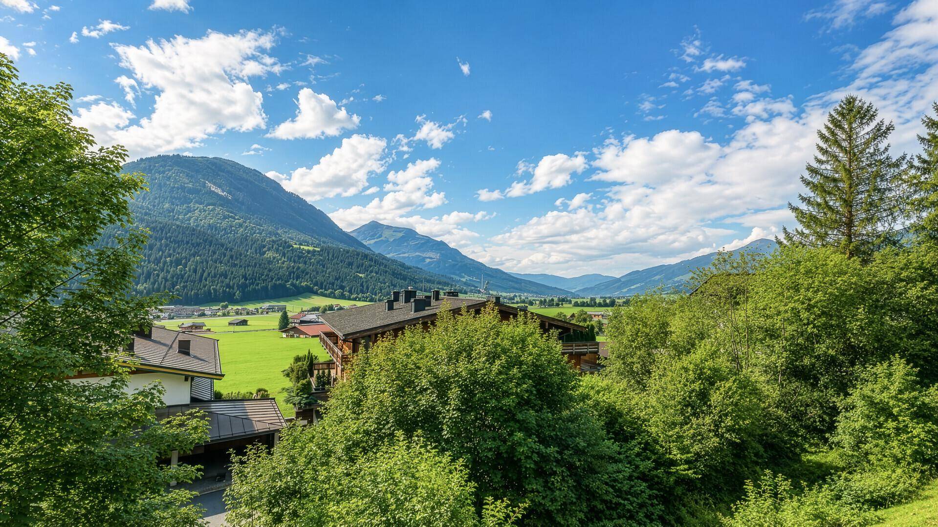 Malerische Landschaft mit Häusern in einem grünen Tal umgeben von Bergen.