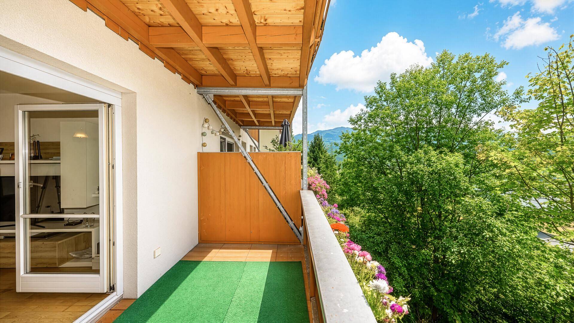 Balkon mit Kunstrasen, Blumenkästen und weitem Blick auf die Berge.
