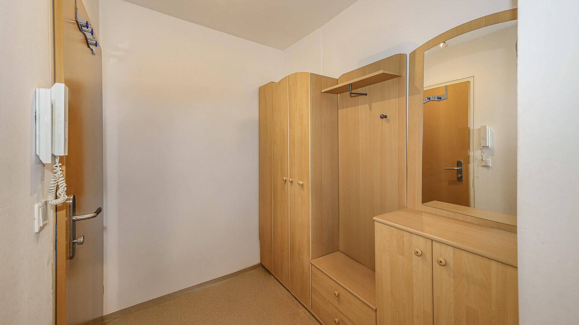 Flur mit Einbauschränken aus hellem Holz und Spiegel.