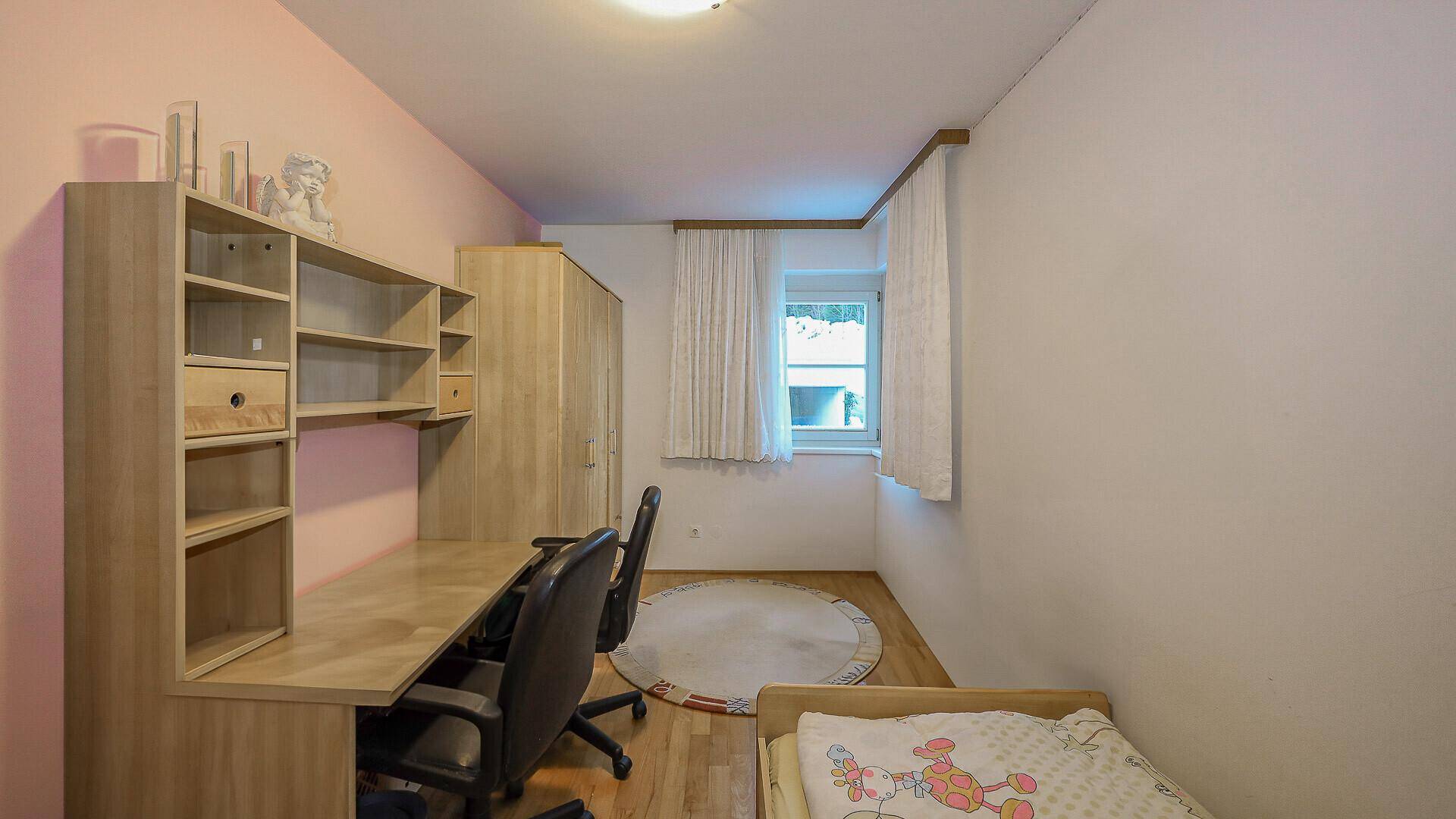 Kinderzimmer oder Büro mit Schreibtisch, Regal und Einzelbett.