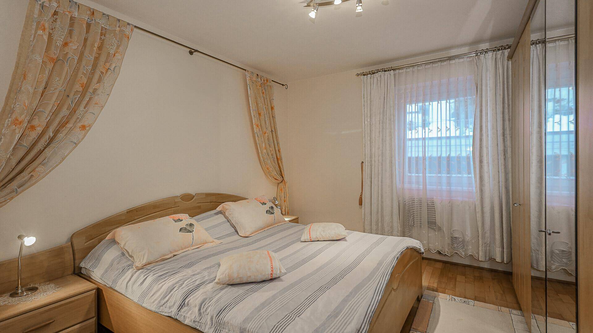 Gemütliches Schlafzimmer mit Holzbett, Kleiderschrank und Vorhängen.