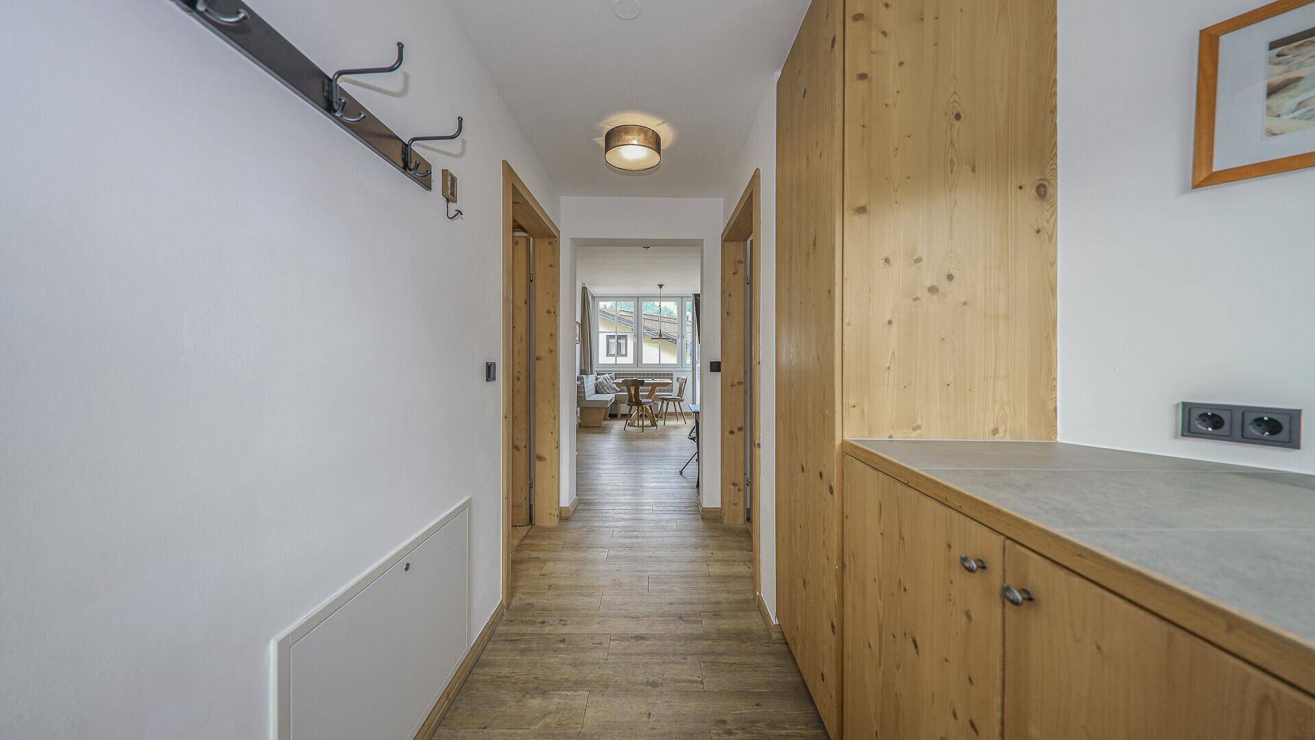 Heller Flur mit Holzschränken und Garderobe, führt zu weiteren Zimmern.