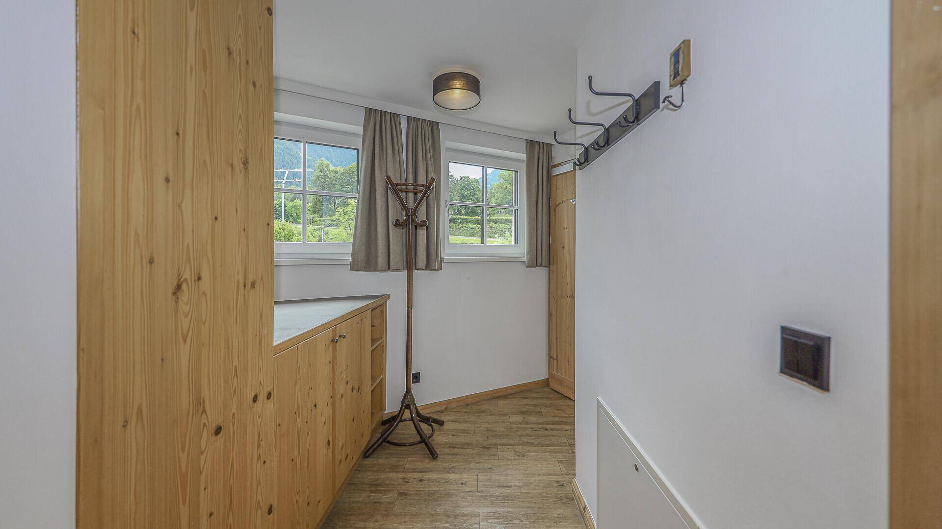 Eingangsbereich mit Garderobe und Holzschränken, bietet Stauraum und Tageslicht.