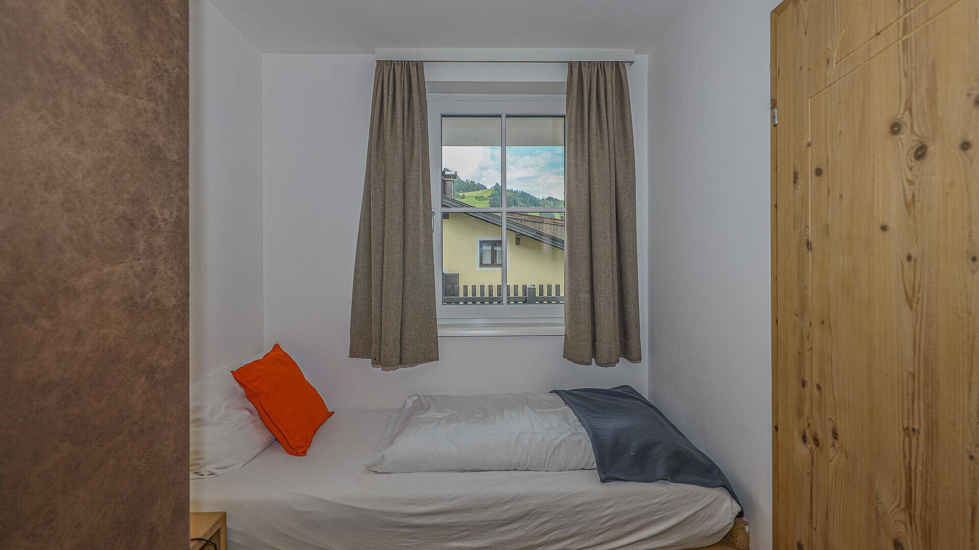 Kleines Schlafzimmer mit Einzelbett und Fenster, bietet Blick auf die Umgebung.