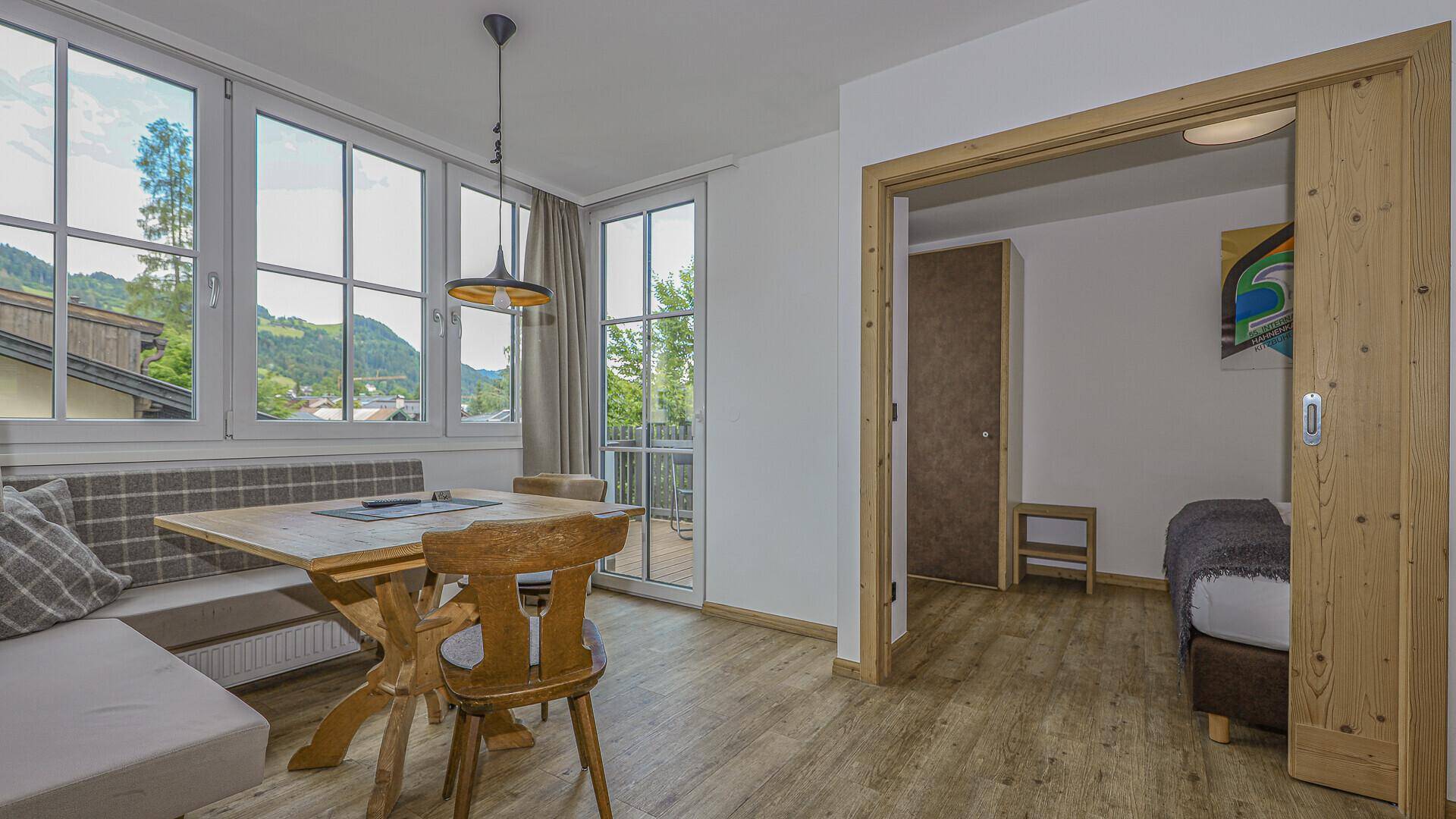 Essbereich mit Holztisch und Eckbank, angrenzend an ein Schlafzimmer mit Bergblick.