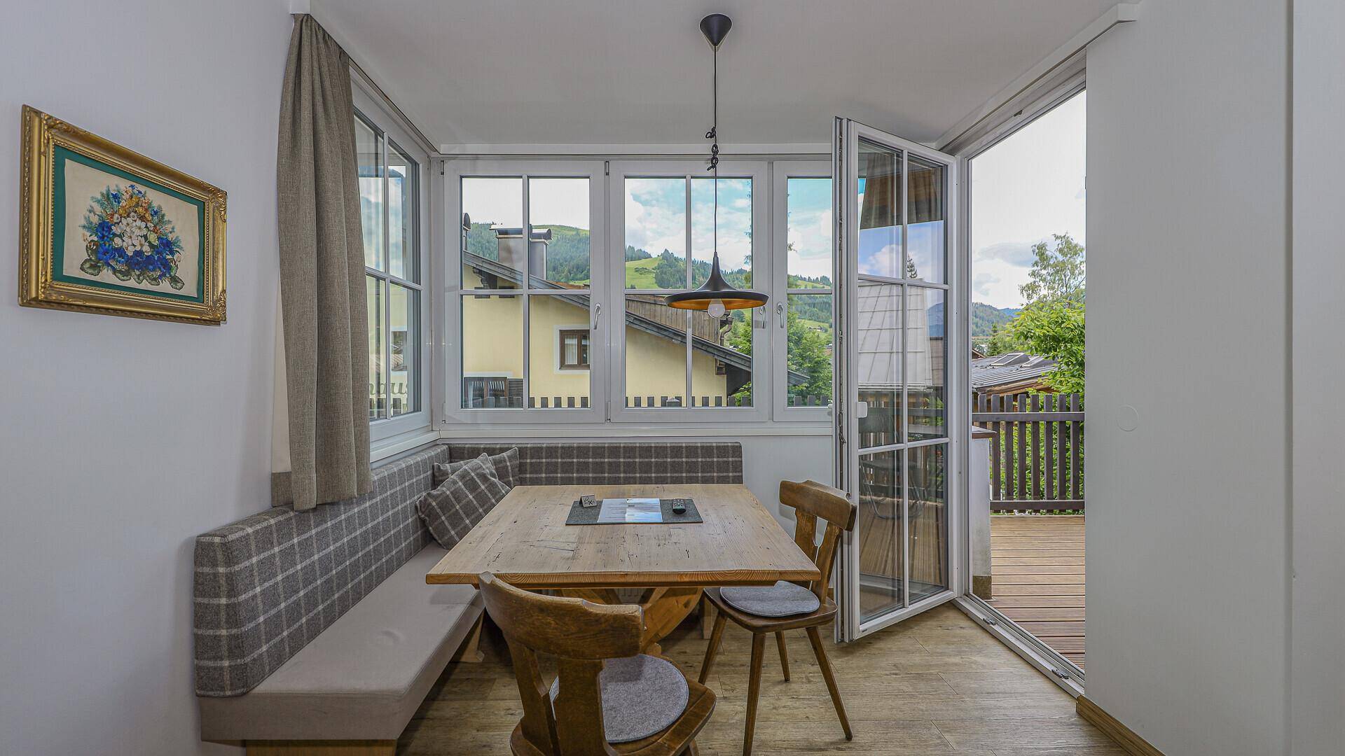 Gemütlicher Essbereich mit Holztisch, Eckbank und Zugang zum Balkon mit Bergblick.