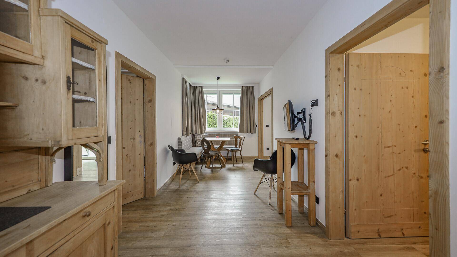 Heller Eingangsbereich mit Holzboden, traditionellen Holzmöbeln und Blick in den Essbereich.