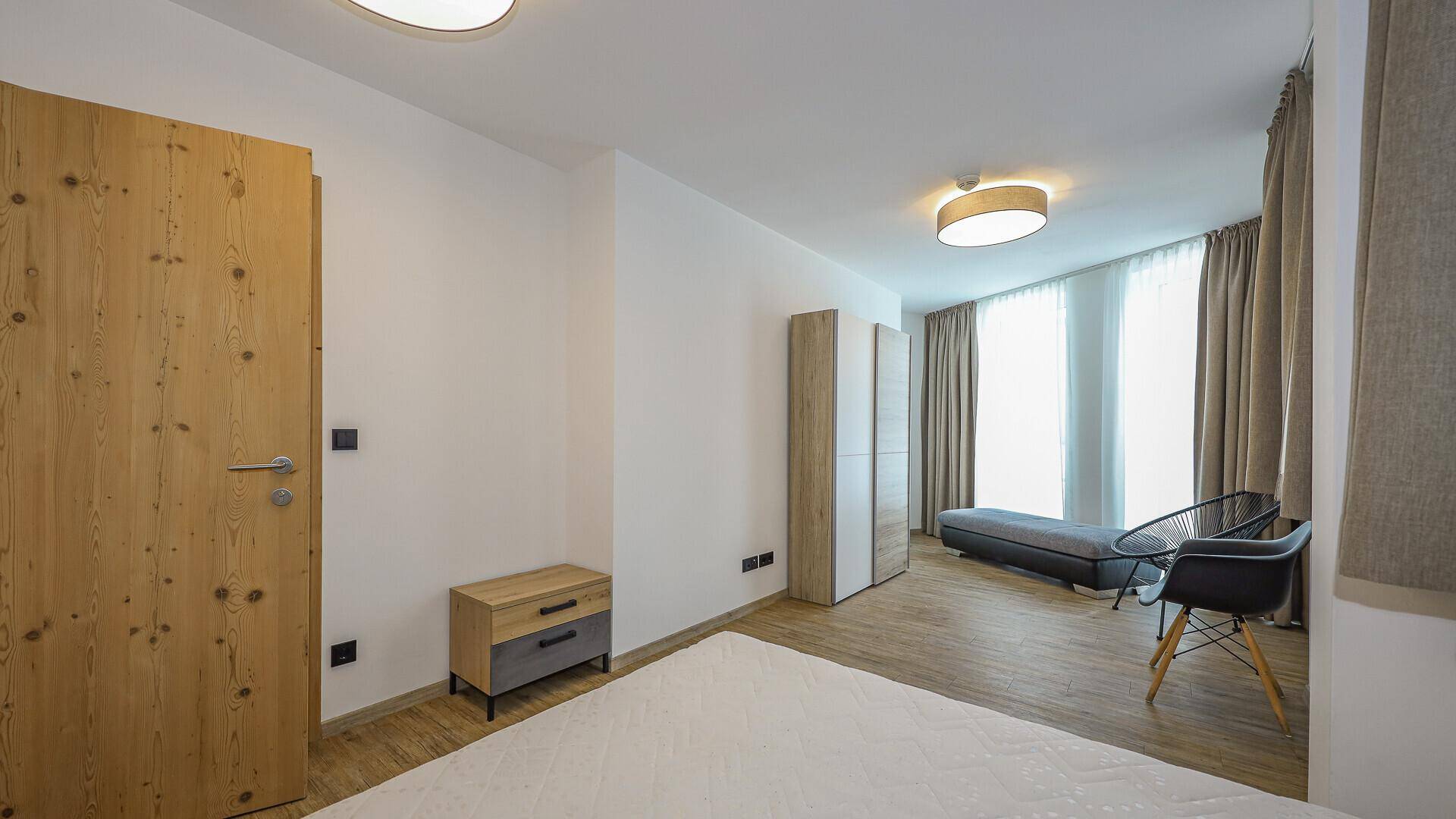 Geräumiges Schlafzimmer mit Doppelbett, Holzboden und großen Fenstern für viel Tageslicht.