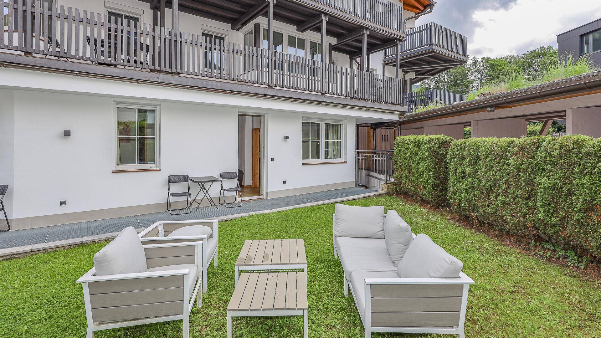 Gepflegter Gartenbereich mit modernen Outdoor-Sitzmöbeln und Blick auf das Apartmentgebäude.