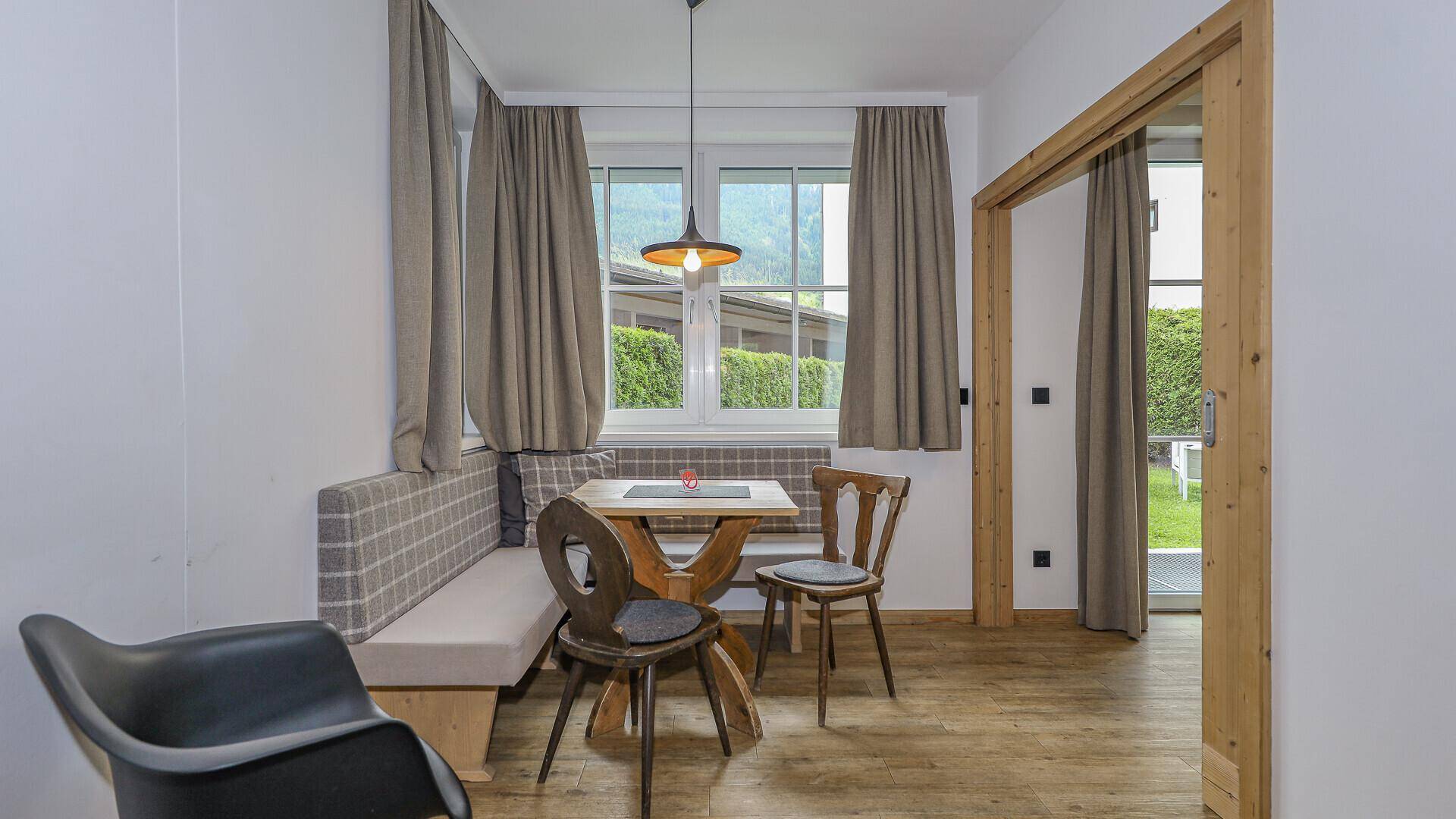 Gemütlicher Essbereich mit Holztisch, Eckbank und Stühlen, umgeben von hellen Wänden und Fenstern.