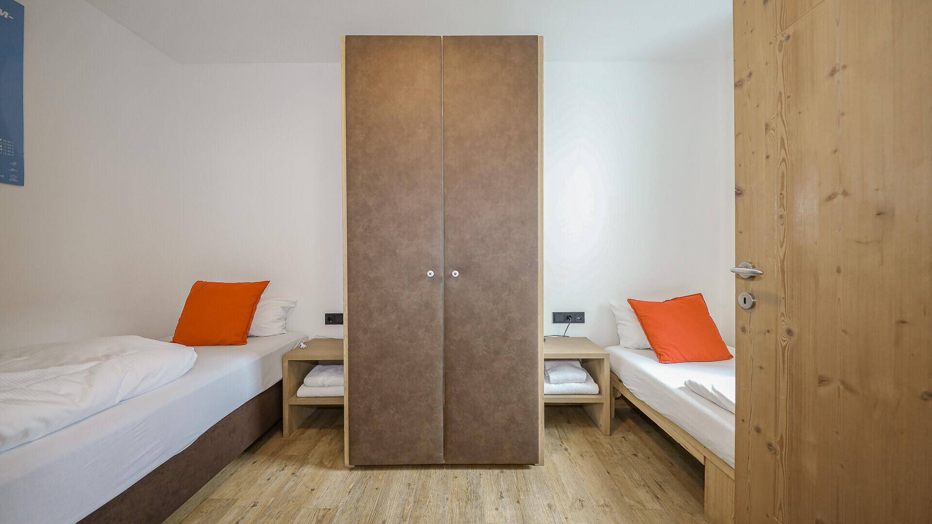 Schlafzimmer mit zwei Einzelbetten, Nachttischen und einem Kleiderschrank.