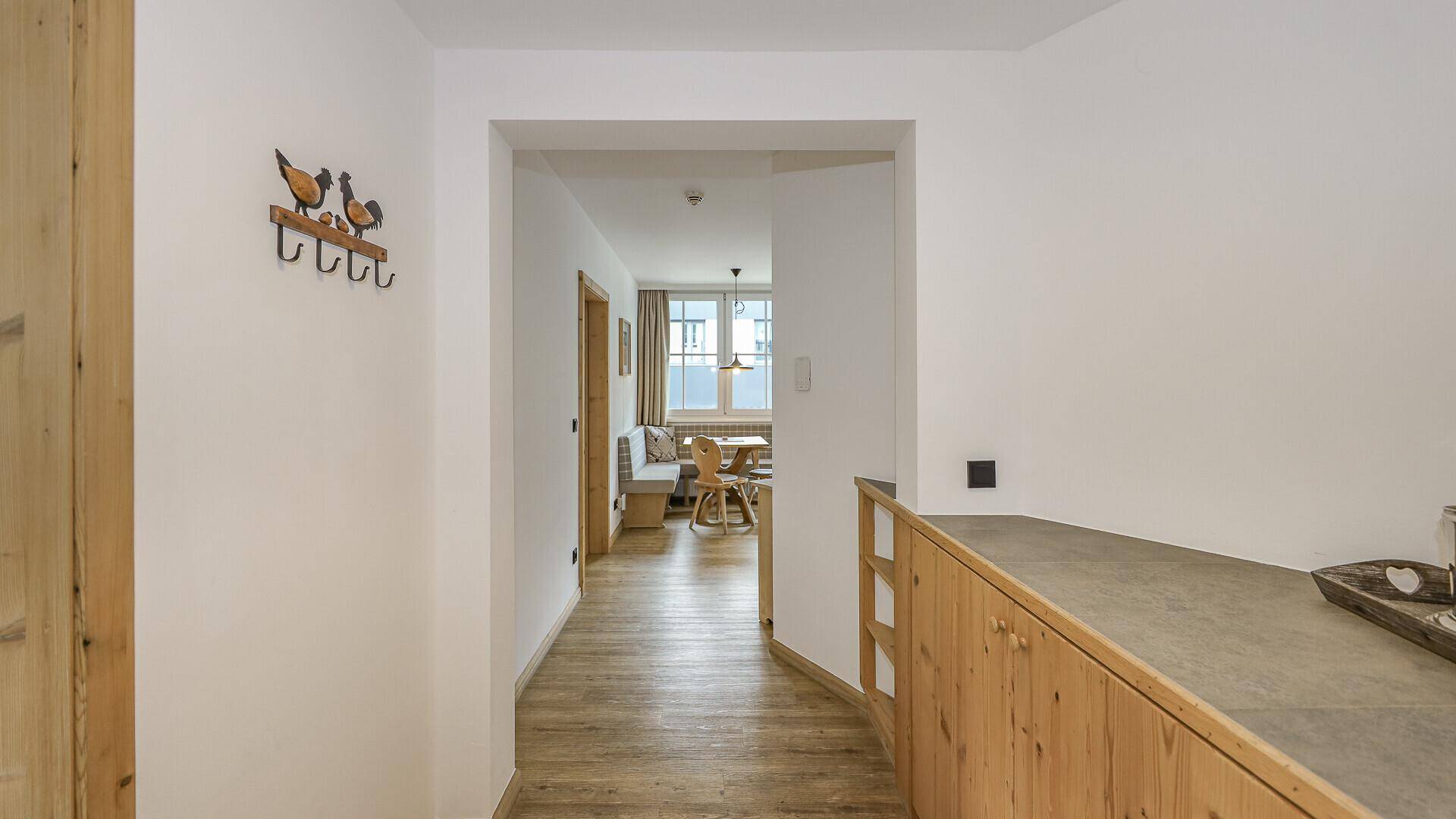 Heller Flur mit Holzboden und Garderobe, der zum Essbereich führt.