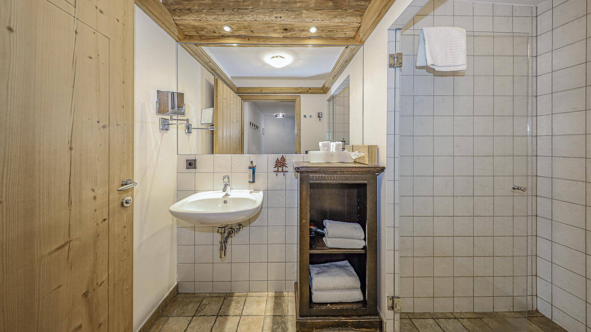 Modernes Badezimmer mit Duschkabine, Waschbecken und Holzdecke.