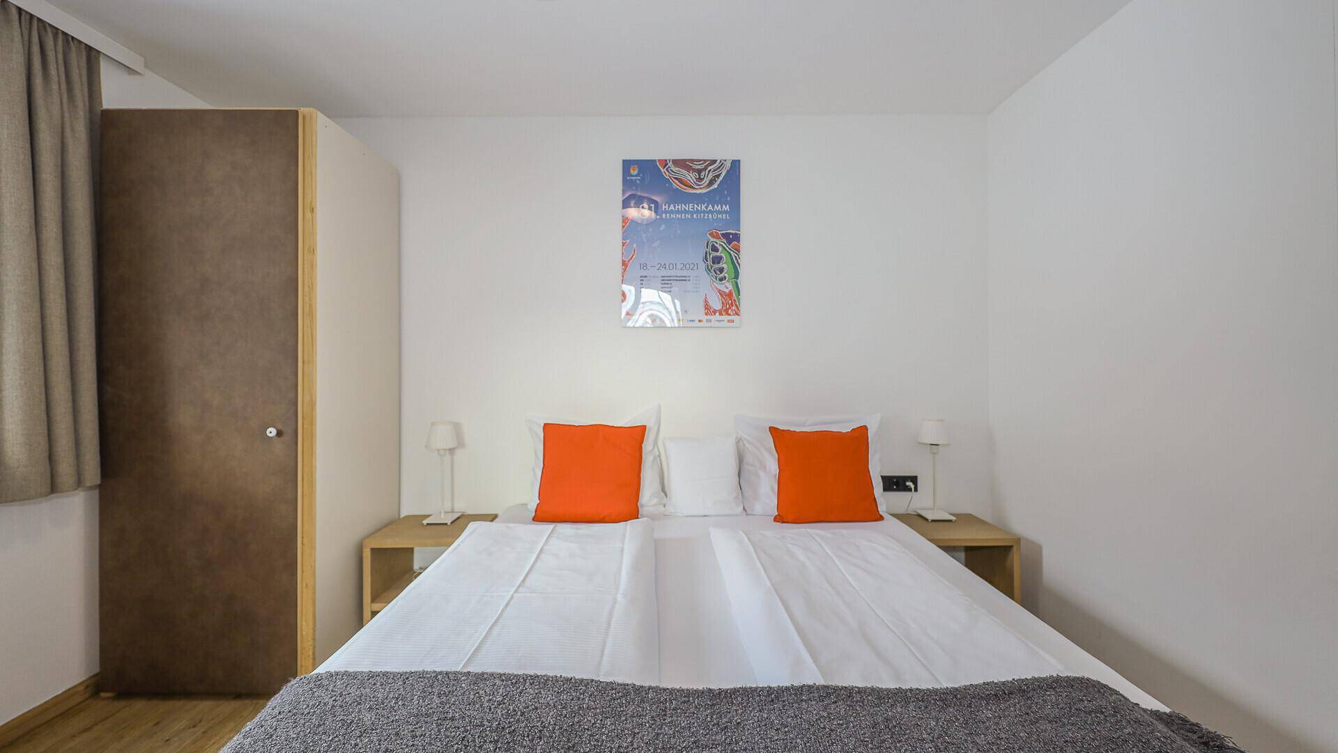 Helles Schlafzimmer mit Doppelbett, Nachttischen und schlichtem Kleiderschrank.