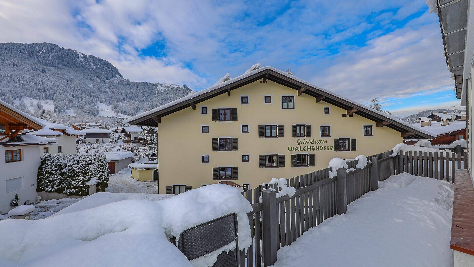 Traditionelles Gästehaus Walchshofer in verschneiter Alpenlandschaft mit Bergblick.