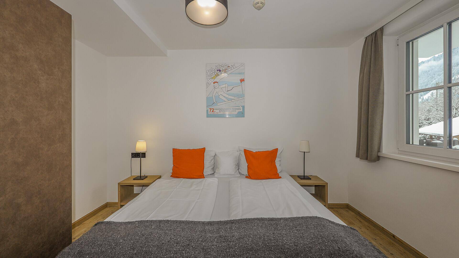 Gemütliches Schlafzimmer mit Doppelbett, Nachttischen und Fenster mit Blick nach draußen.