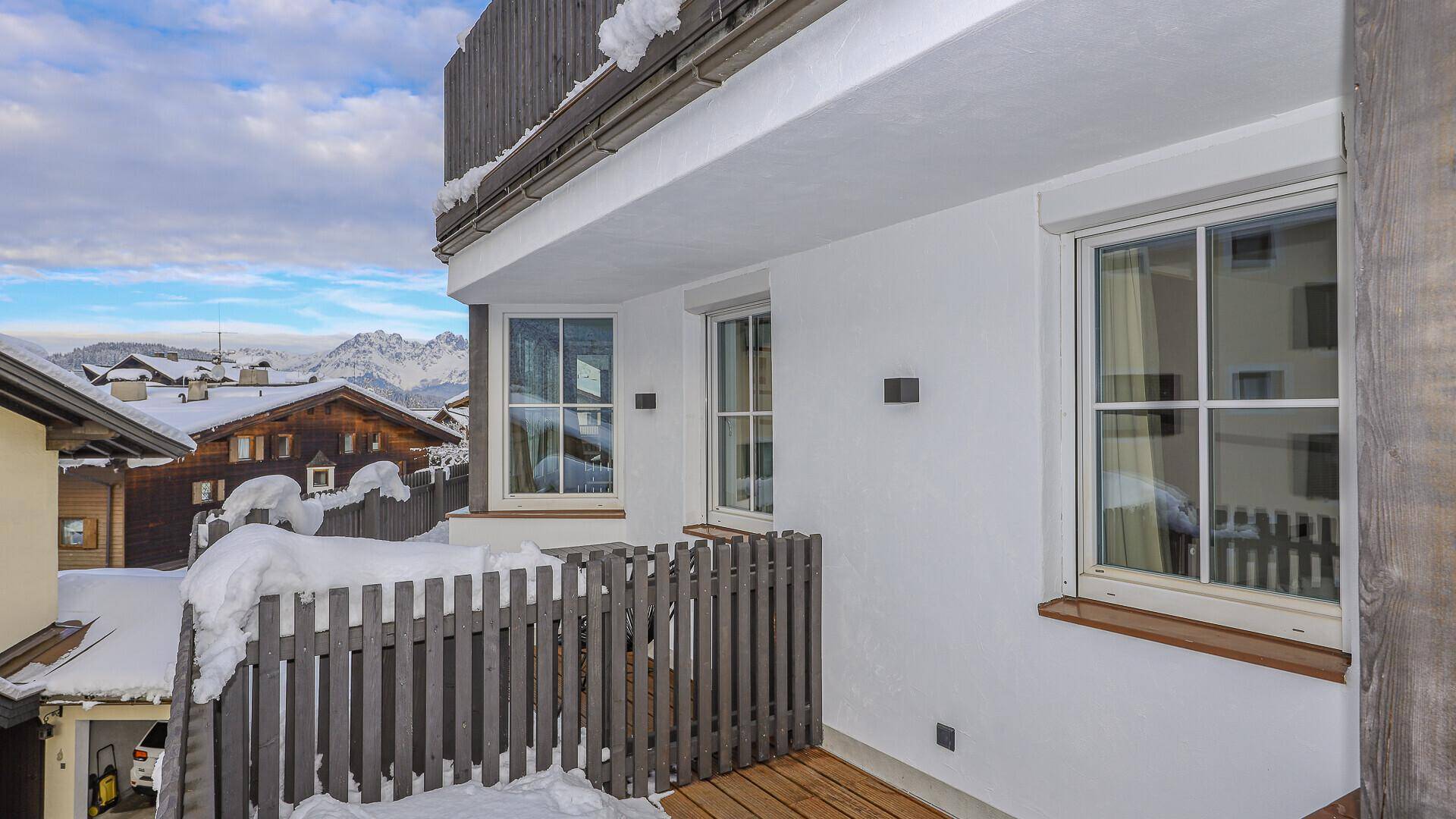 Kleiner Balkon mit Holzgeländer und malerischem Blick auf die verschneite Bergwelt.
