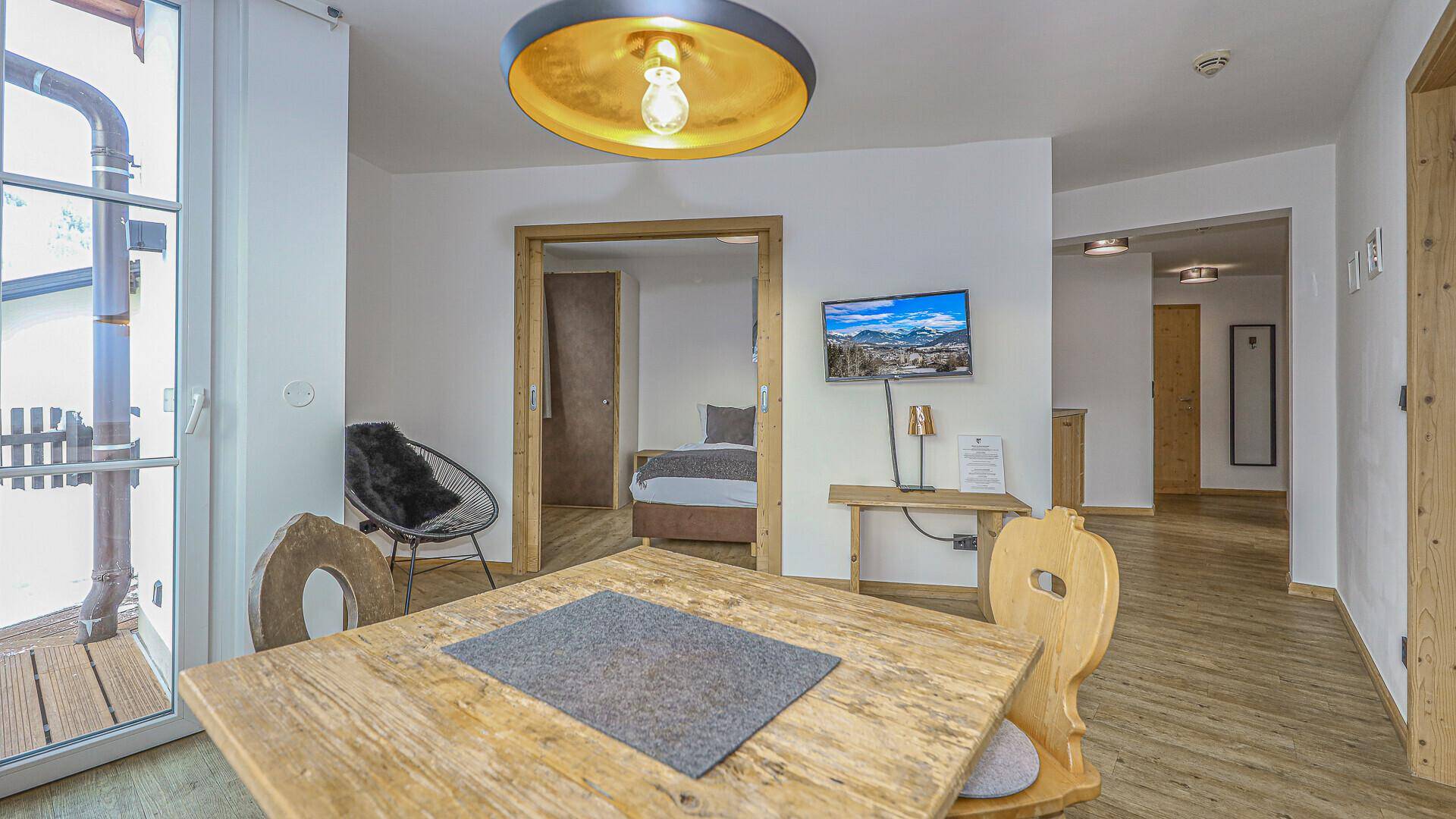 Essbereich mit Holztisch und Zugang zu einem Schlafzimmer, hell und freundlich gestaltet.