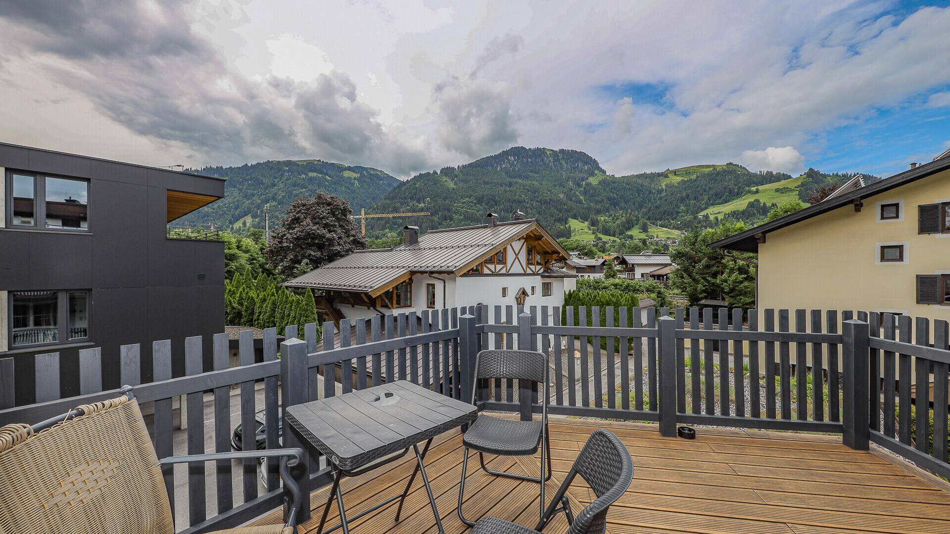 Balkon mit Holzboden und Sitzgelegenheiten, bietet einen weiten Blick auf die Berge.