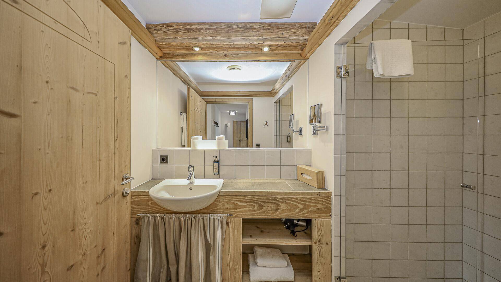 Modernes Badezimmer mit Holzwaschtisch, Spiegel und begehbarer Dusche.