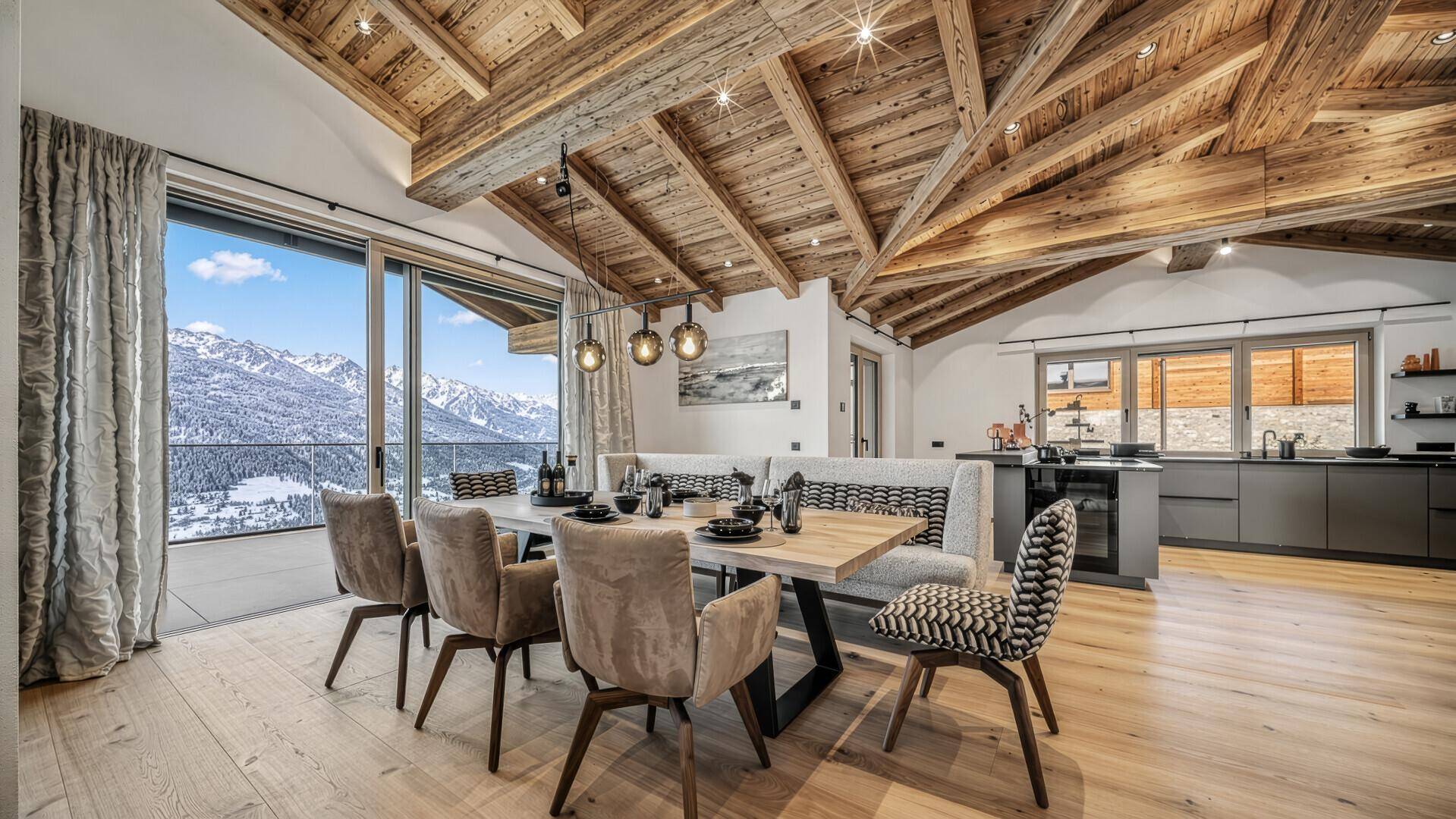 Eleganter Essbereich mit Holzbalkendecke, modernen Möbeln und offener Küche im Hintergrund.
