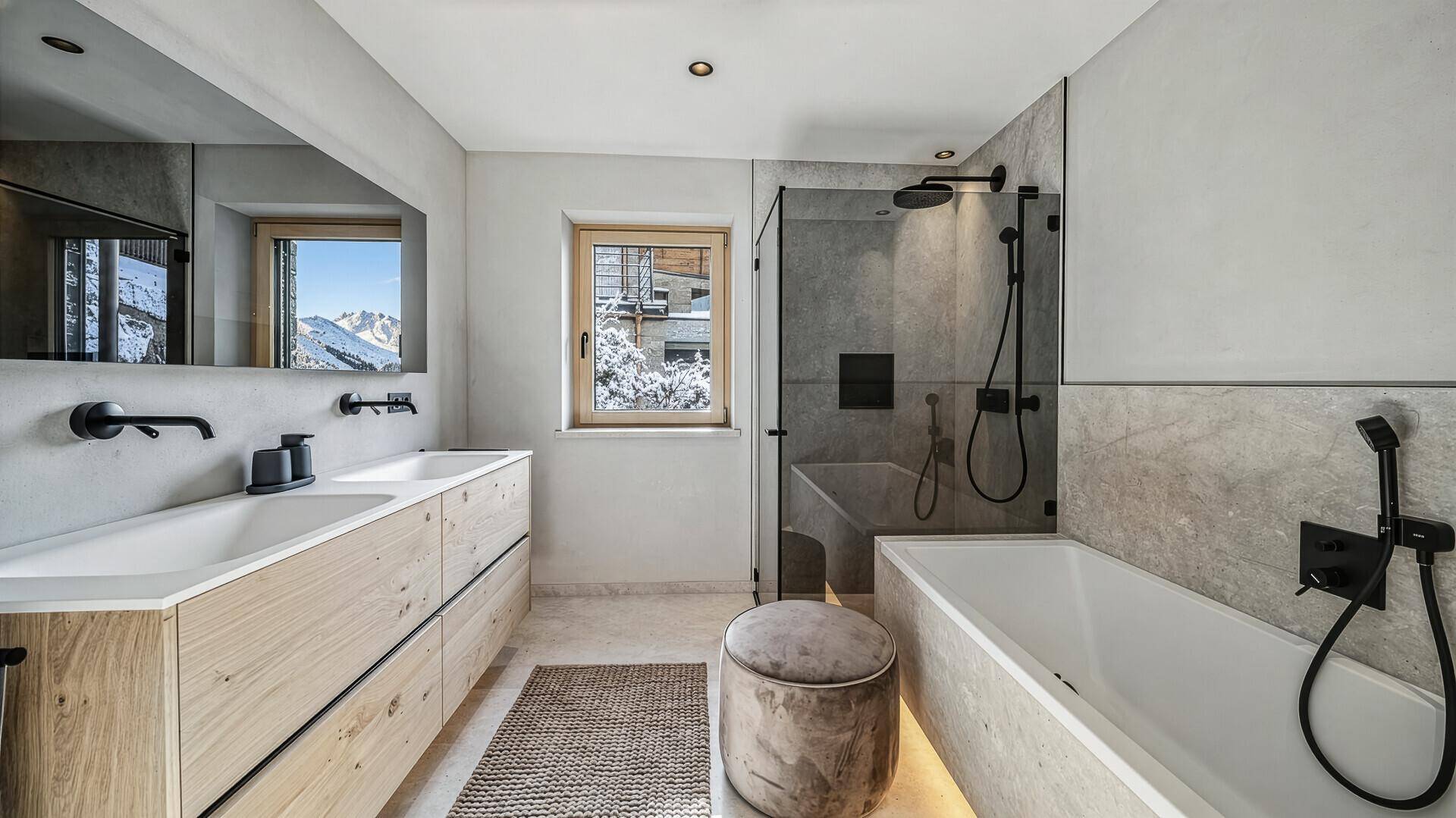 Modernes Badezimmer mit Doppelwaschbecken, Badewanne, Dusche und Fenster mit Bergblick.