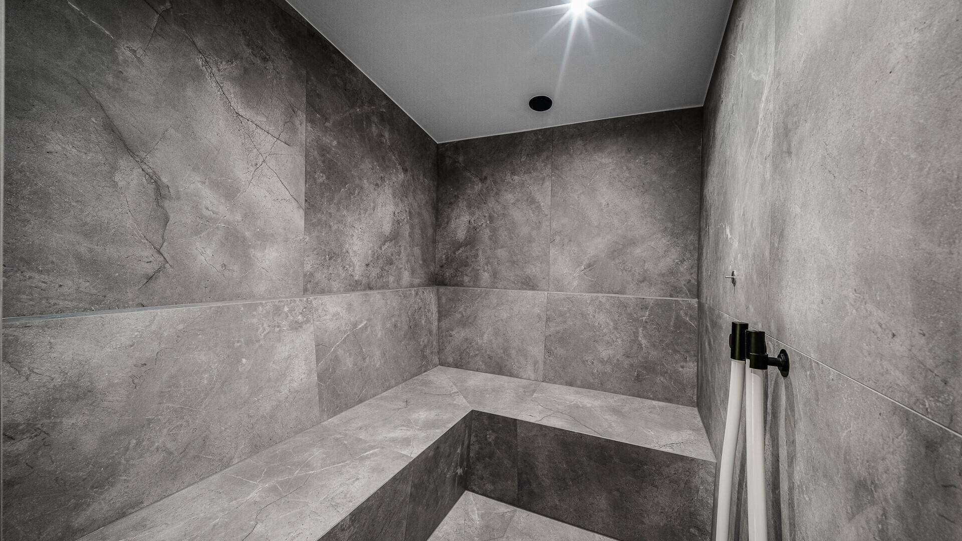 Modernes Dampfbad mit grauen Fliesen und minimalistischem Design.