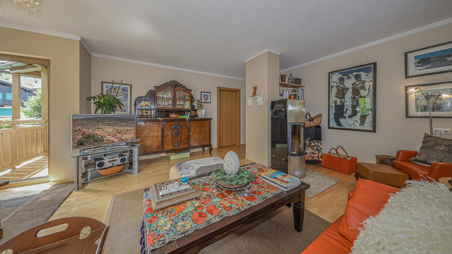 Traditionelles Wohnzimmer mit Holzboden, Kaminofen und direktem Zugang zu einem Balkon.