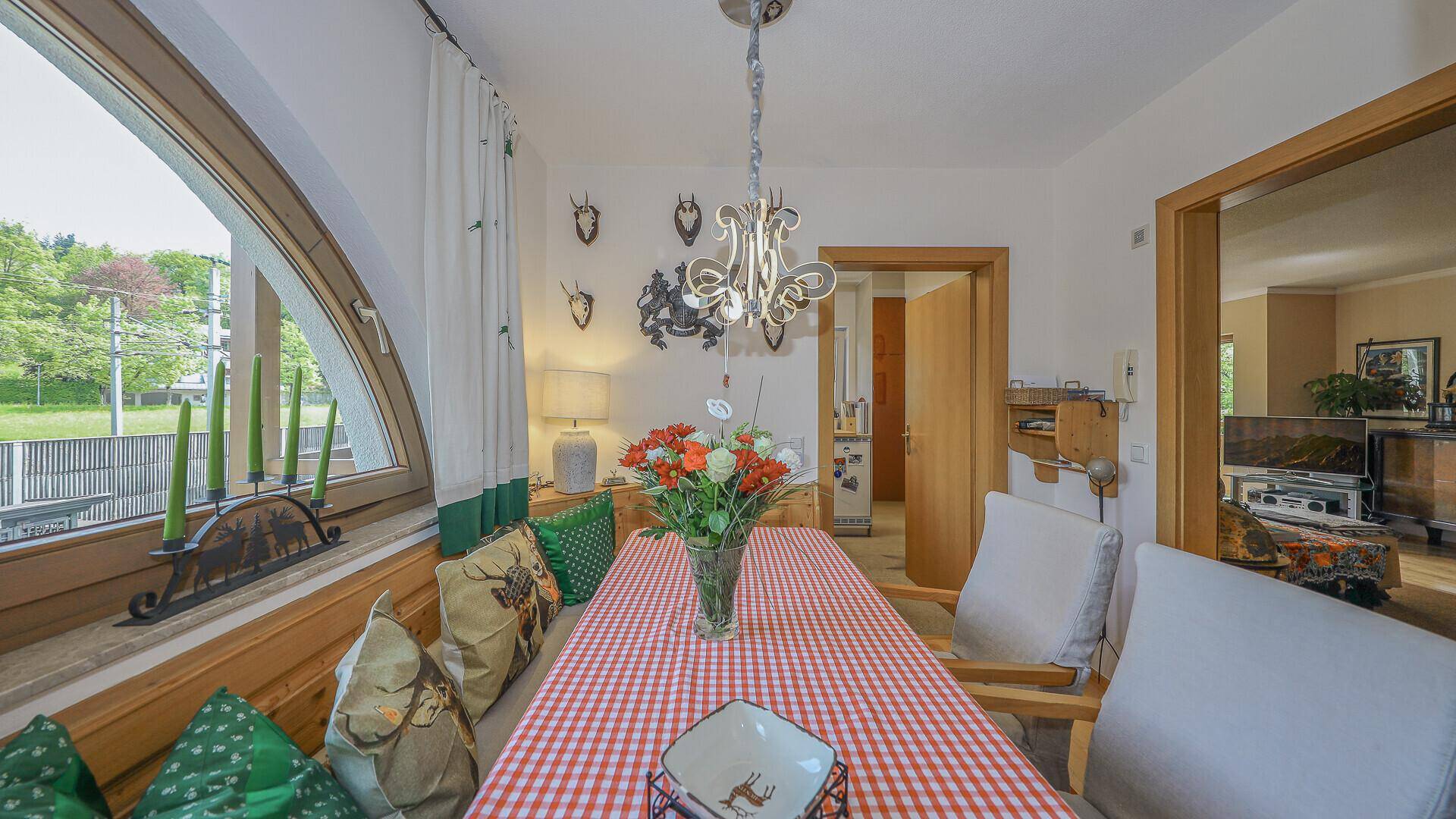Traditioneller Essbereich mit Eckbank, Hirschgeweih-Dekoration und großem Bogenfenster.
