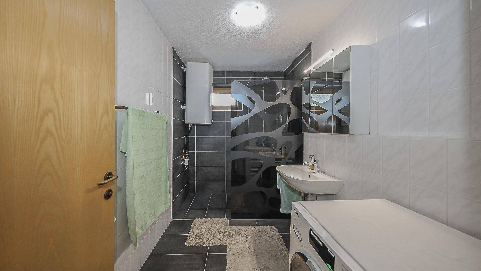 Modernes Badezimmer mit Dusche, Waschbecken und Waschmaschine.
