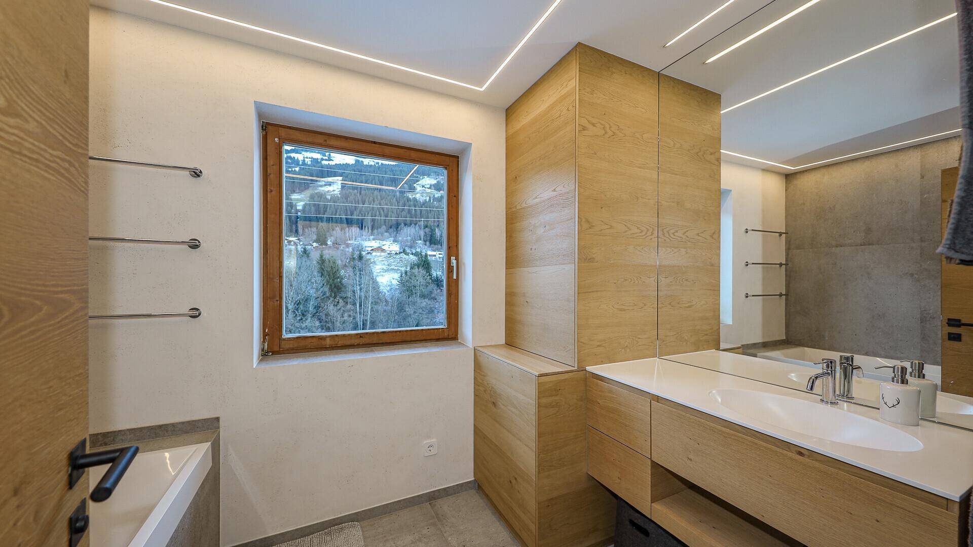 Modernes Badezimmer mit Holzwaschtisch, Einzelwaschbecken und Fenster mit Blick ins Grüne.