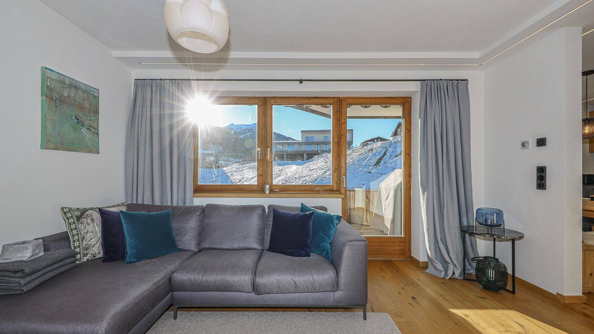 Helles Wohnzimmer mit bequemer Couch und großen Fenstern, die viel Sonnenlicht hereinlassen.