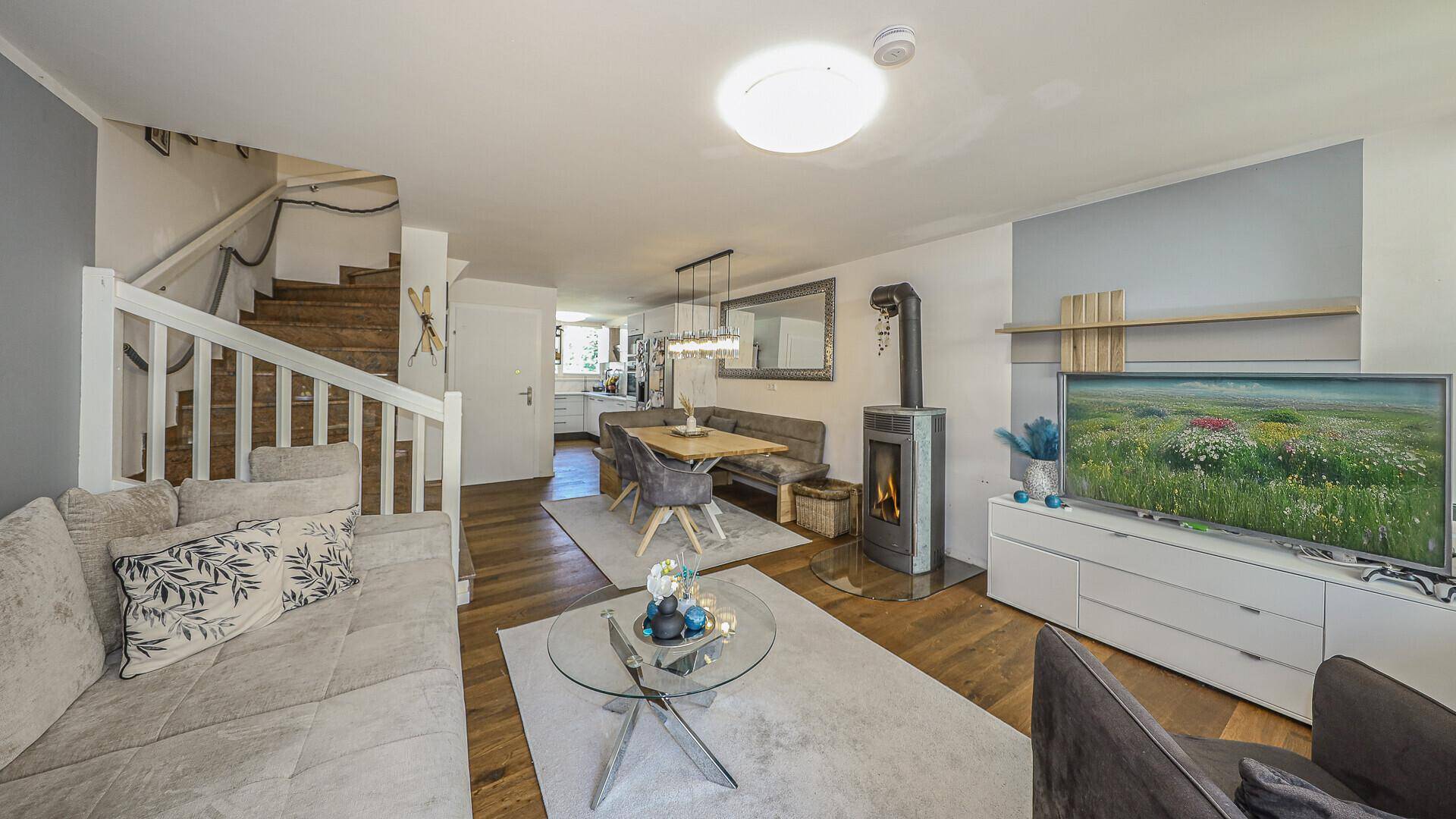Offener Wohn-Essbereich mit Kamin, Holzboden und Blick in den Garten.